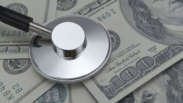 A stethoscope is sitting on top of a pile of money.