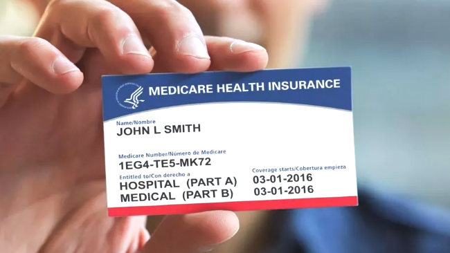 Person holding a Medicare health insurance card, blue and white with red accents; John L. Smith's name and ID number are visible.