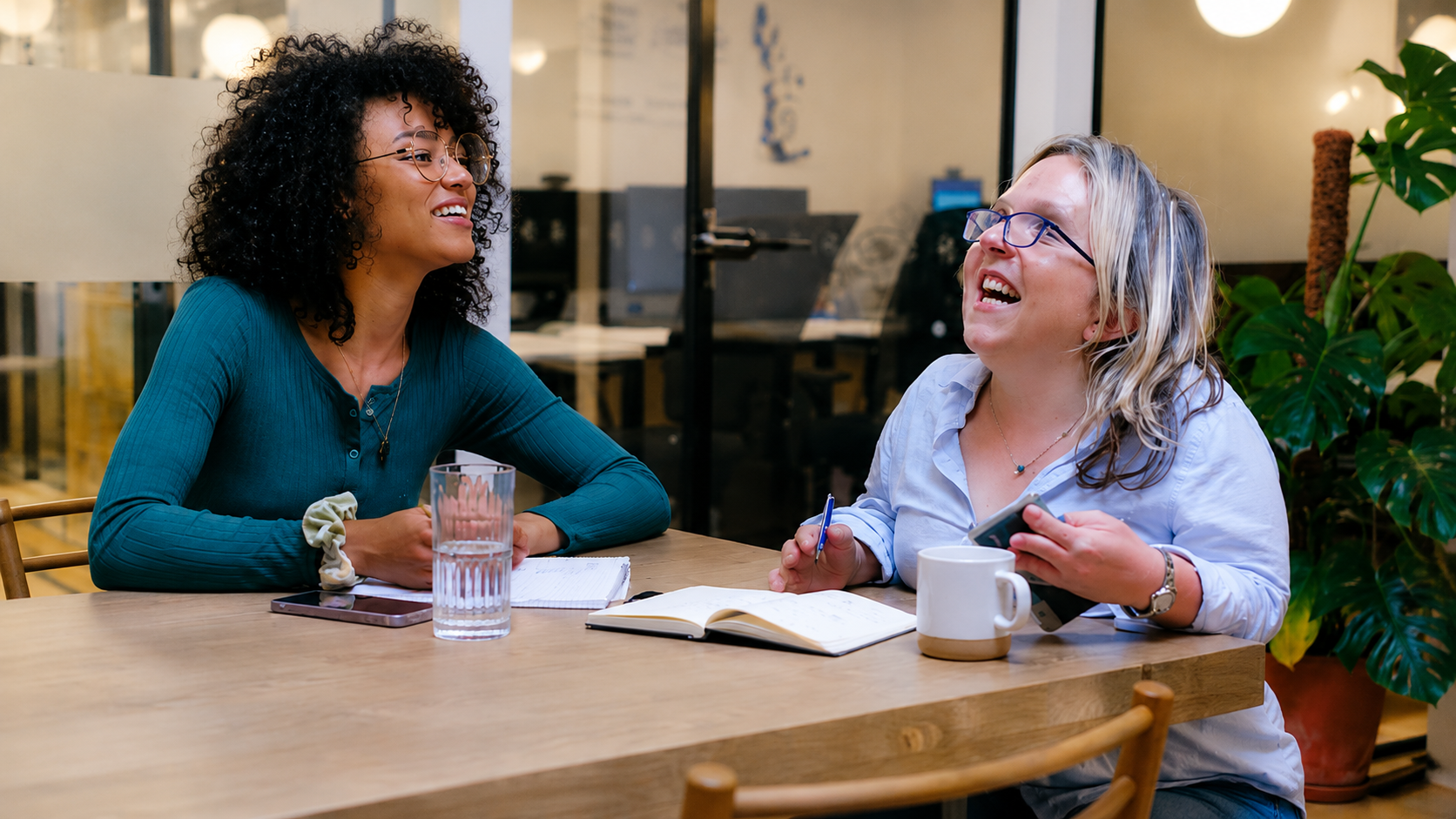 NDIS participant and mental health support worker at a table smiling