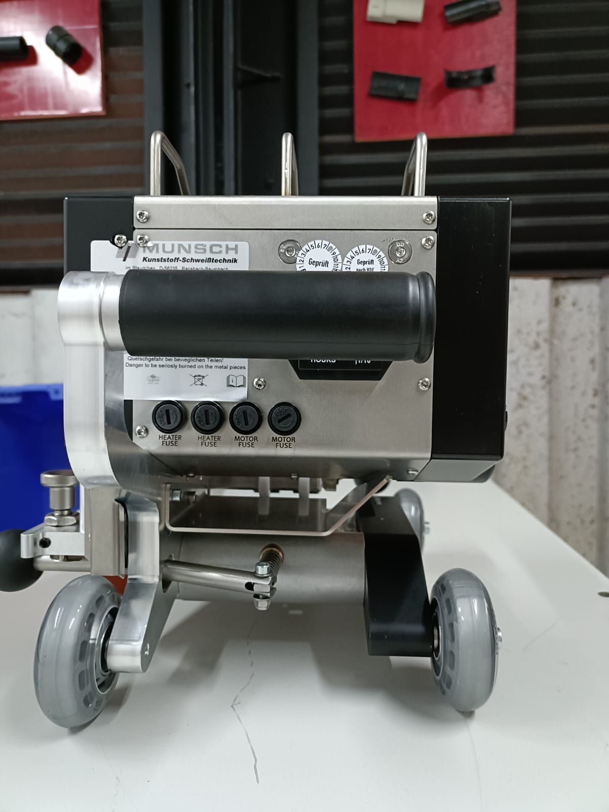 Dispositivo metálico y negro con ruedas, con la etiqueta 