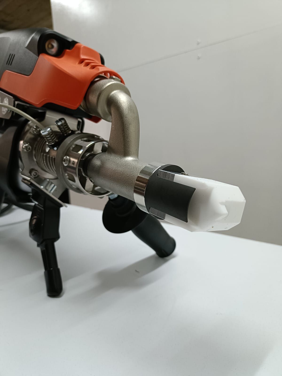 Primer plano de una boquilla de pulverización de pintura, con la punta cubierta con material blanco y cinta negra.