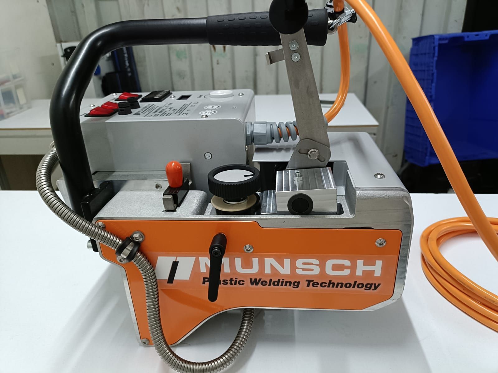 Máquina de soldar plástico MUNSCH de color naranja y plata con mango negro y manguera naranja.