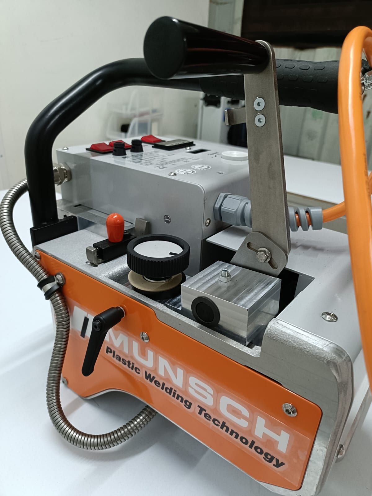 Una máquina de soldar plástico industrial portátil en color naranja y plateado con mango negro, la etiqueta dice 