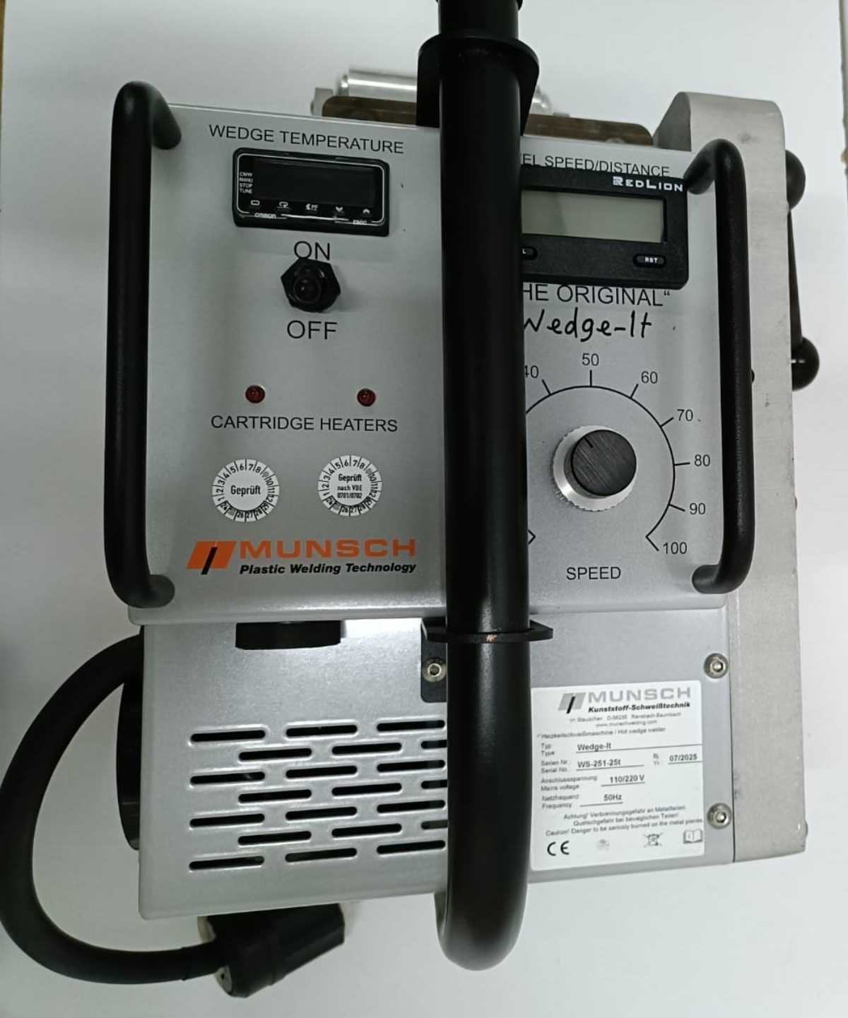 Dispositivo industrial plateado con pantalla digital, diales y mango negro, etiquetado como 