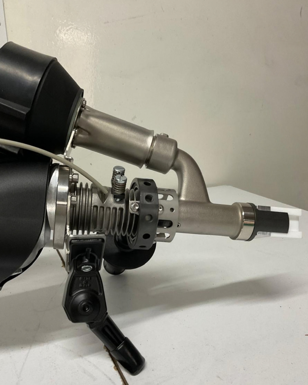 Herramienta de soldadura de color naranja y negro sobre una superficie blanca con fondo gris.