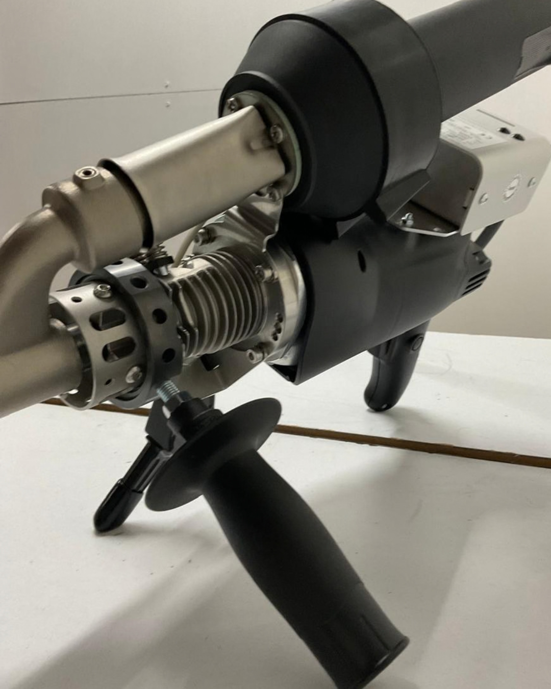 Una herramienta de soldar Munsch negra dentro de un estuche, con un cable de alimentación negro y un mango naranja.