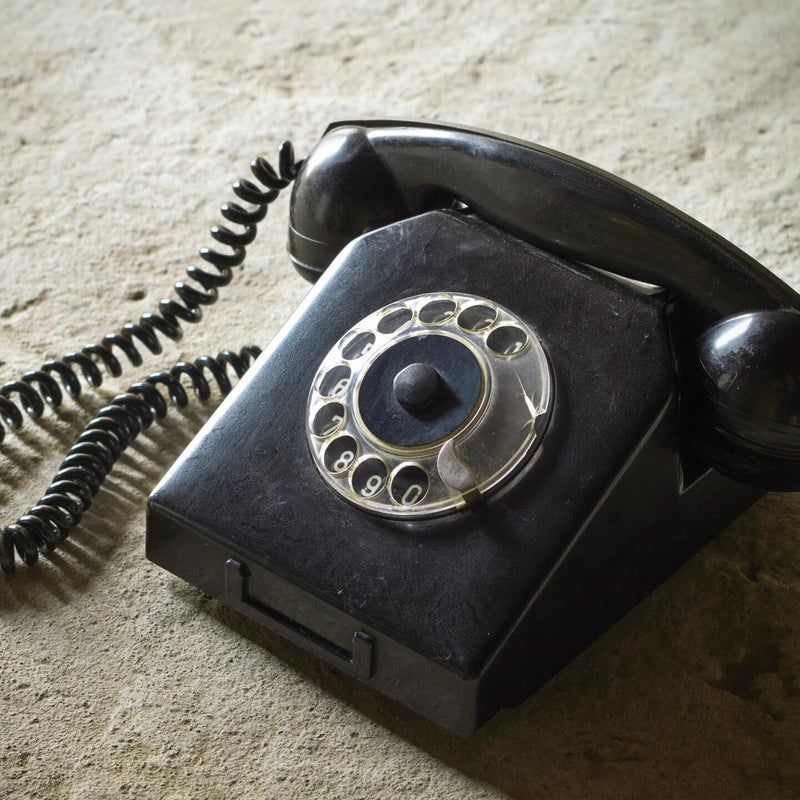 Telefono vintage a disco nero su superficie ruvida.