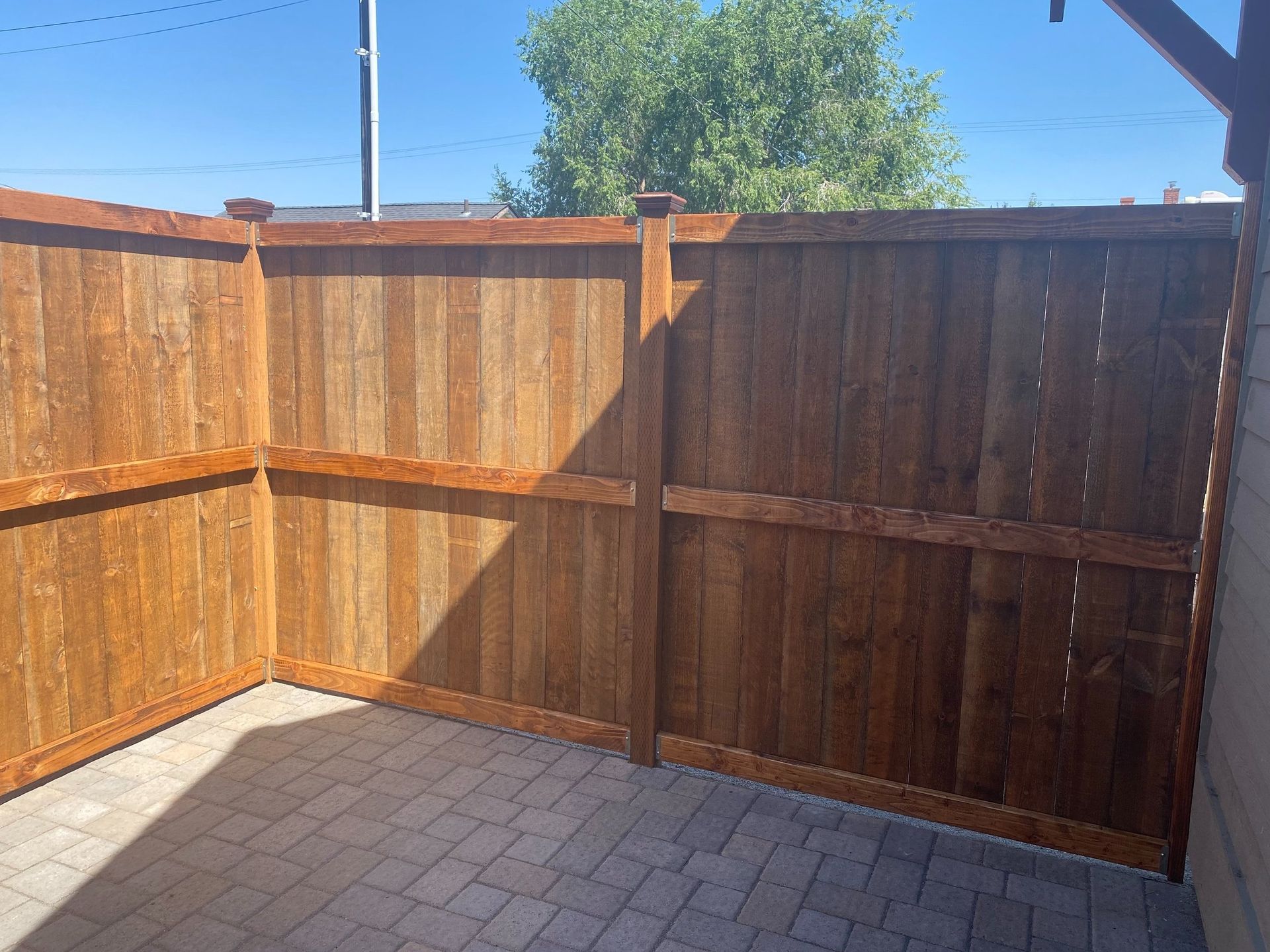 A wooden fence is sitting on top of a brick patio.