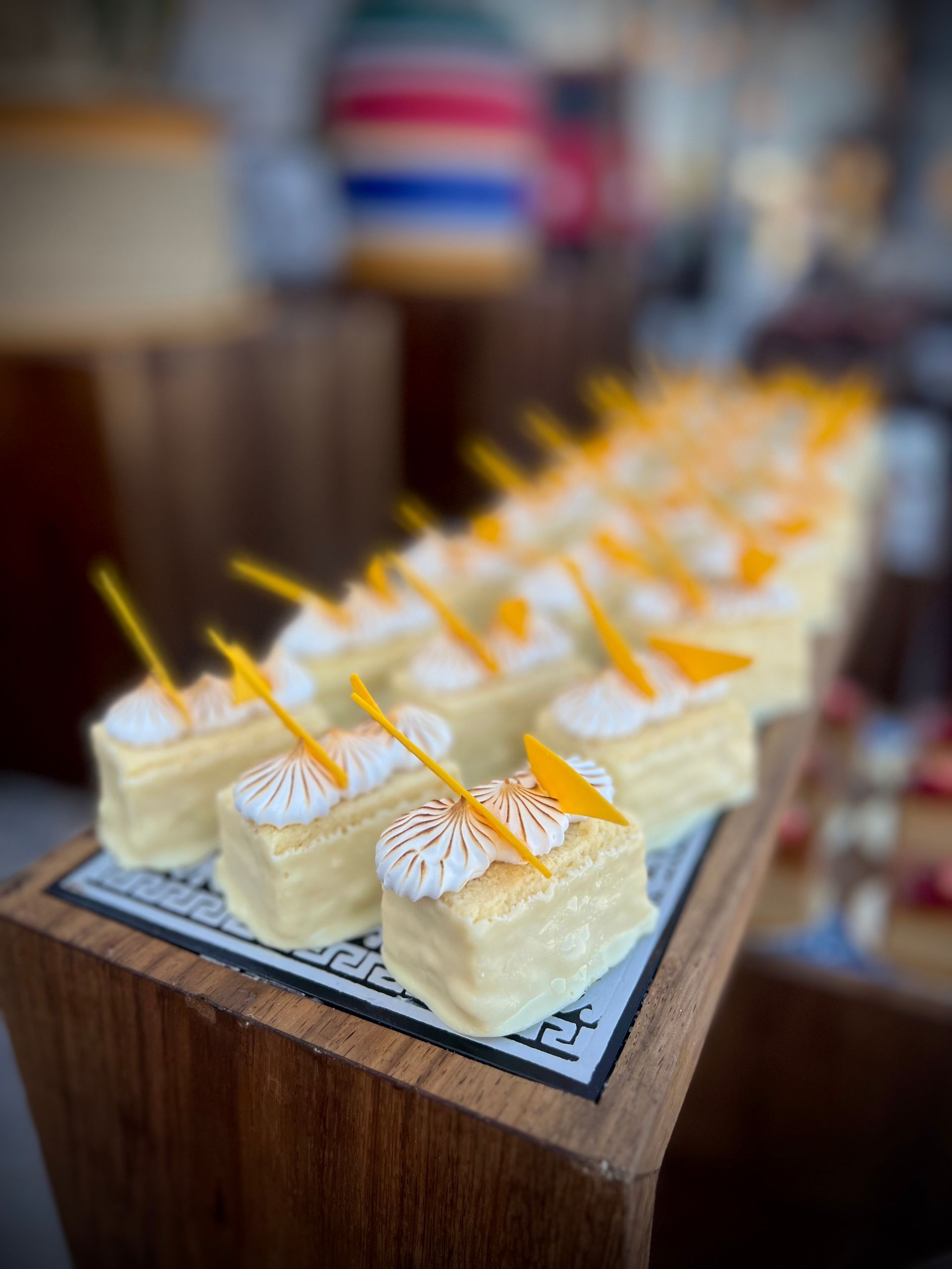 A row of small cakes on a wooden tray on a table.
