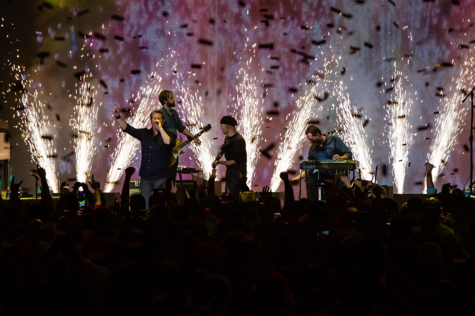 A group of people are standing on a stage with fireworks in the background.