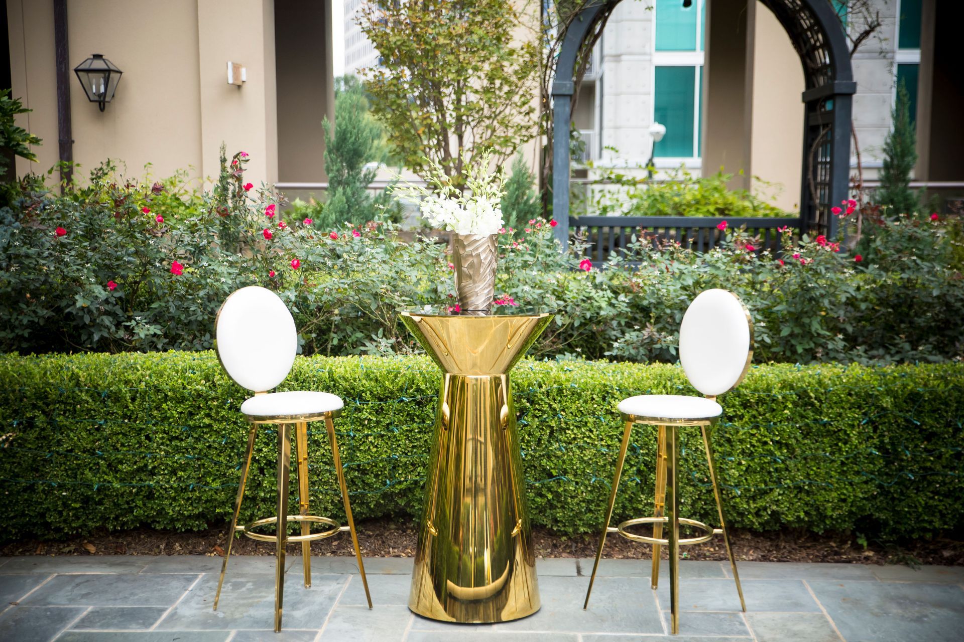 A gold table with two white chairs in front of a house.
