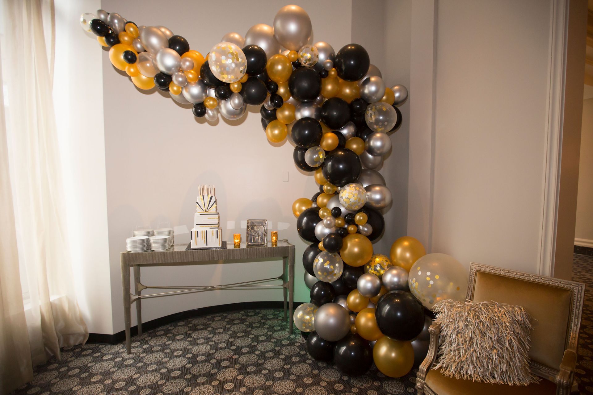 A room decorated with black , gold and silver balloons.