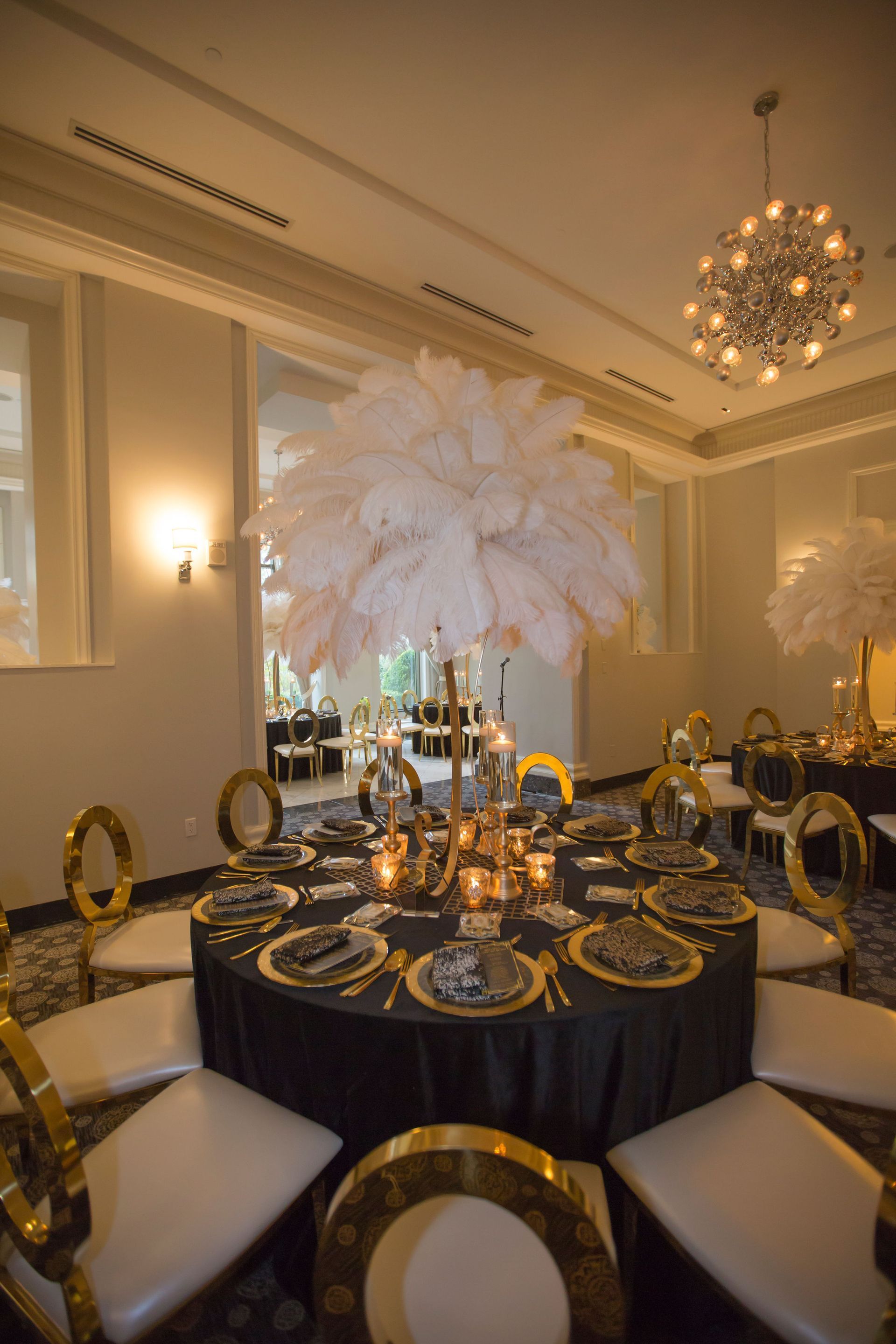 A table set for a wedding reception with a feather centerpiece.