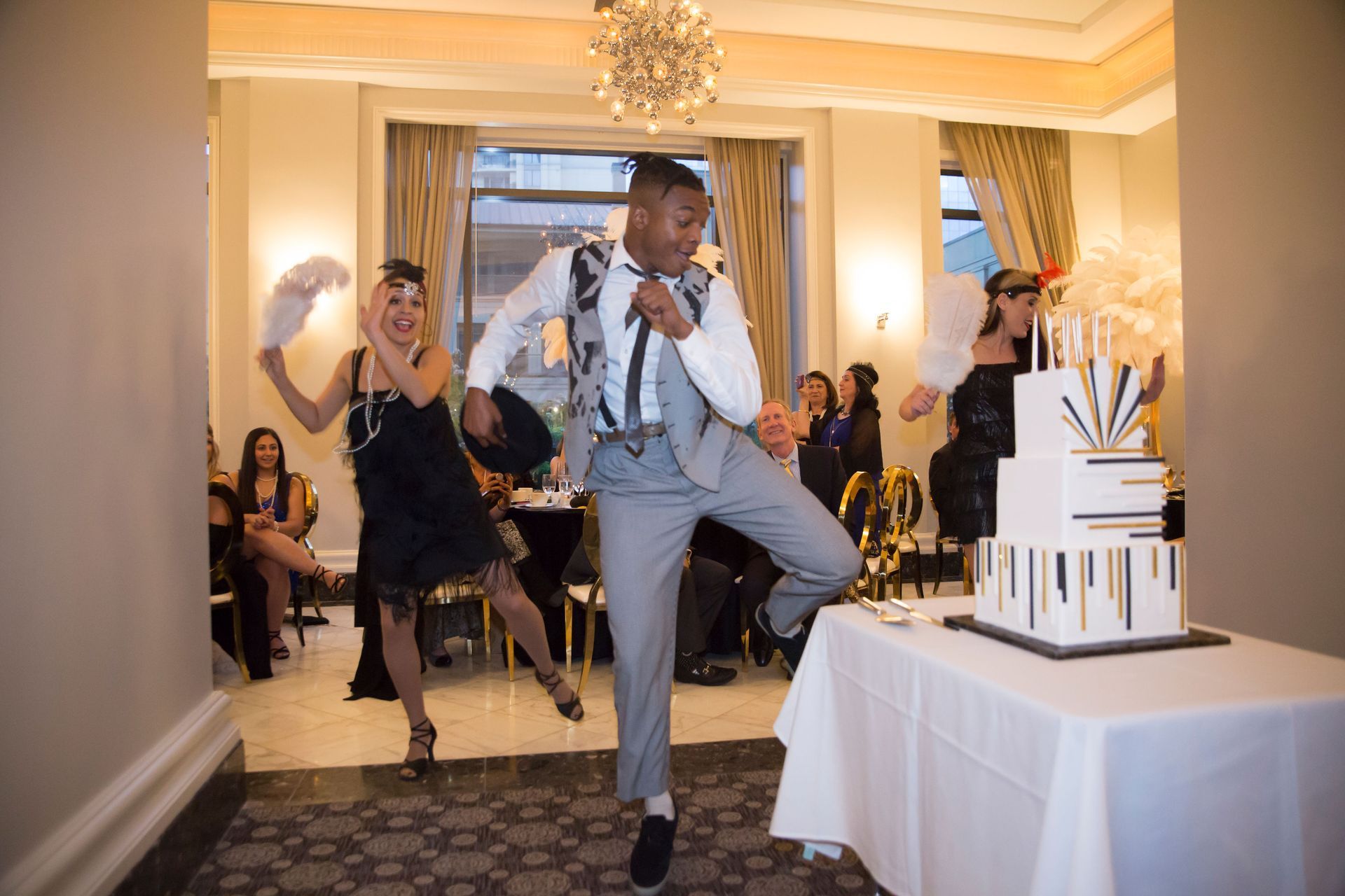 A man in a suit is dancing in front of a cake.