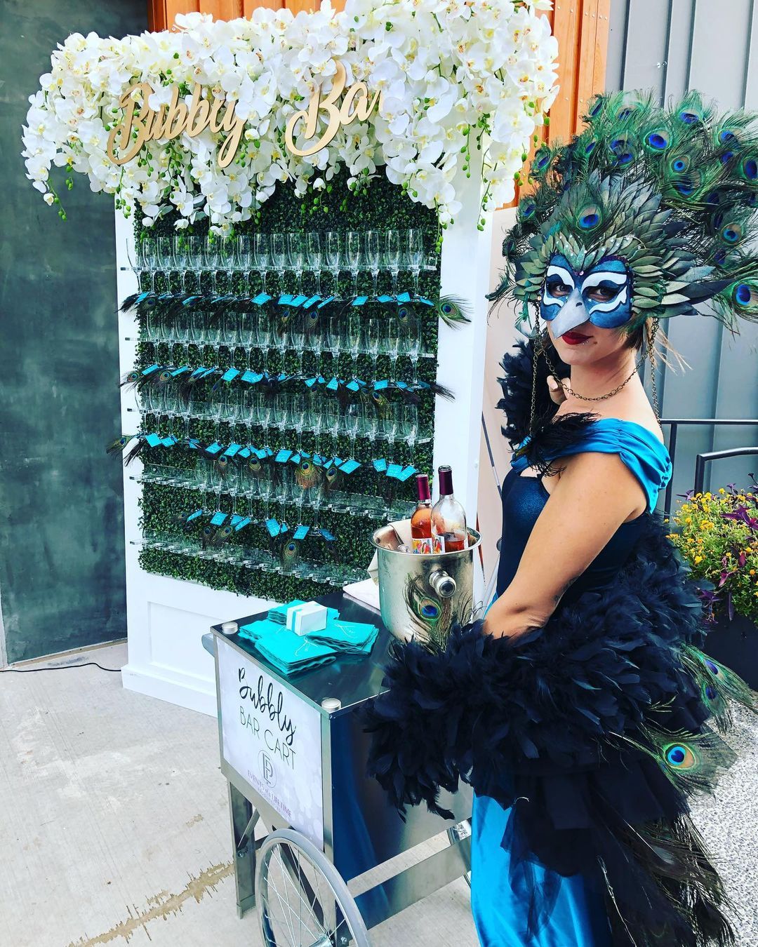 Actress in a mask standing in front of champagne wall
