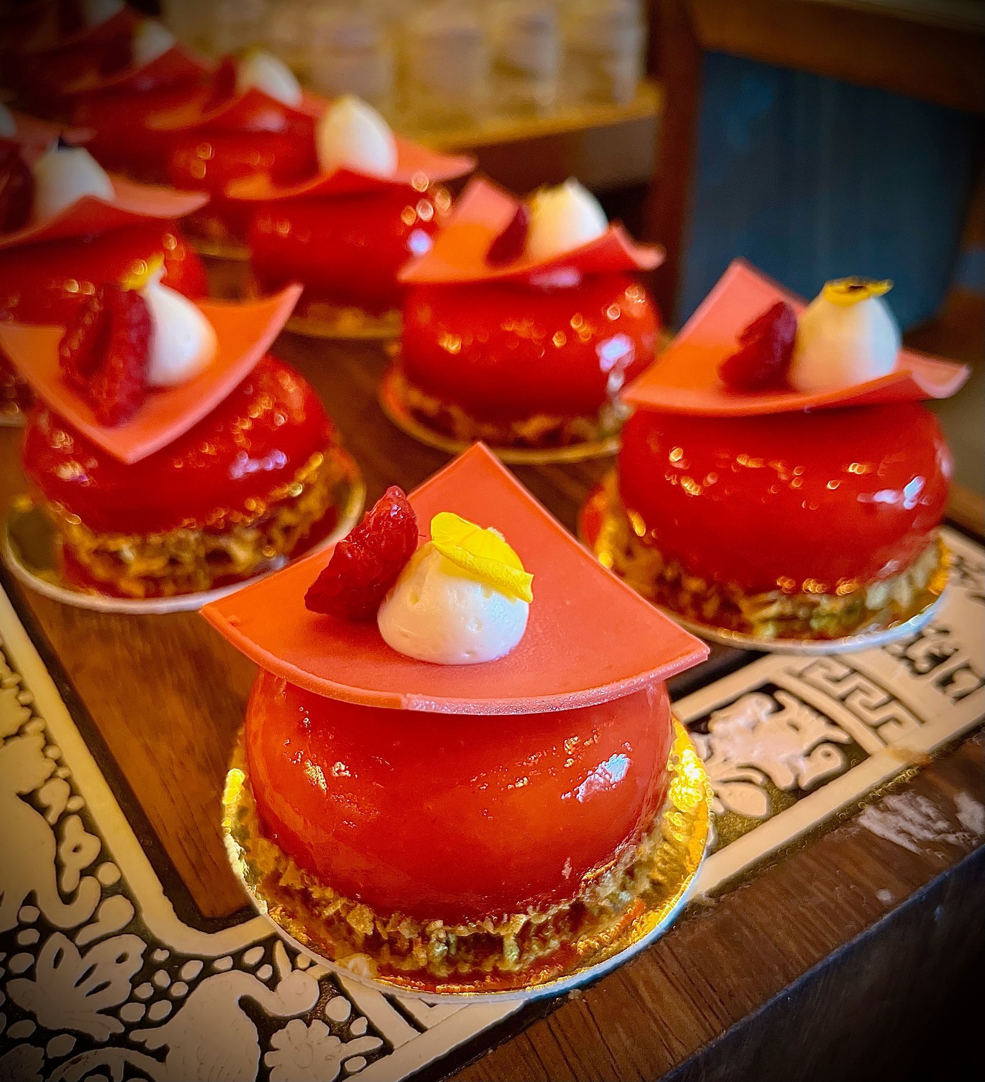 A bunch of red cakes with strawberries on top on a table