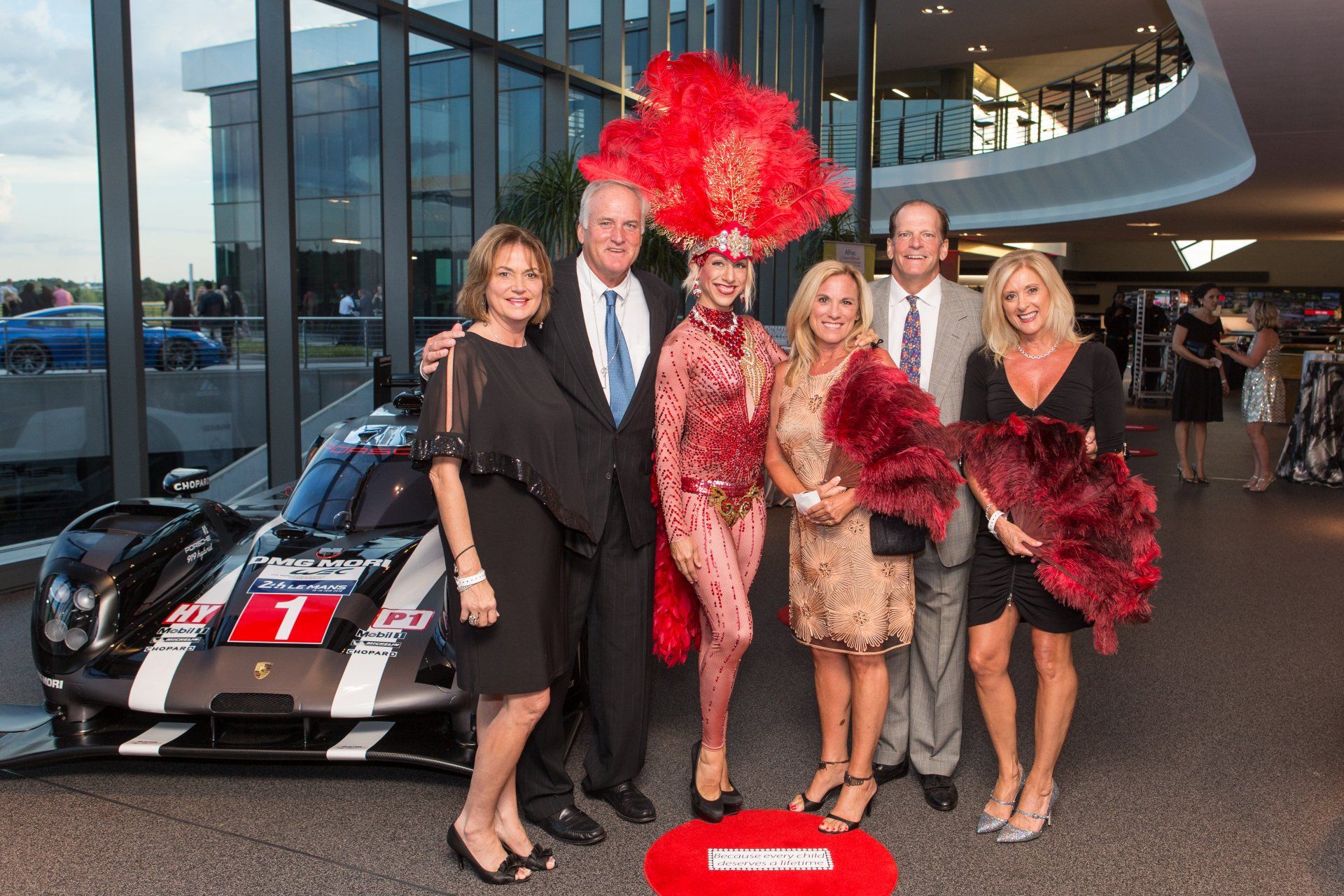 A group of people are posing for a picture in front of a race car.