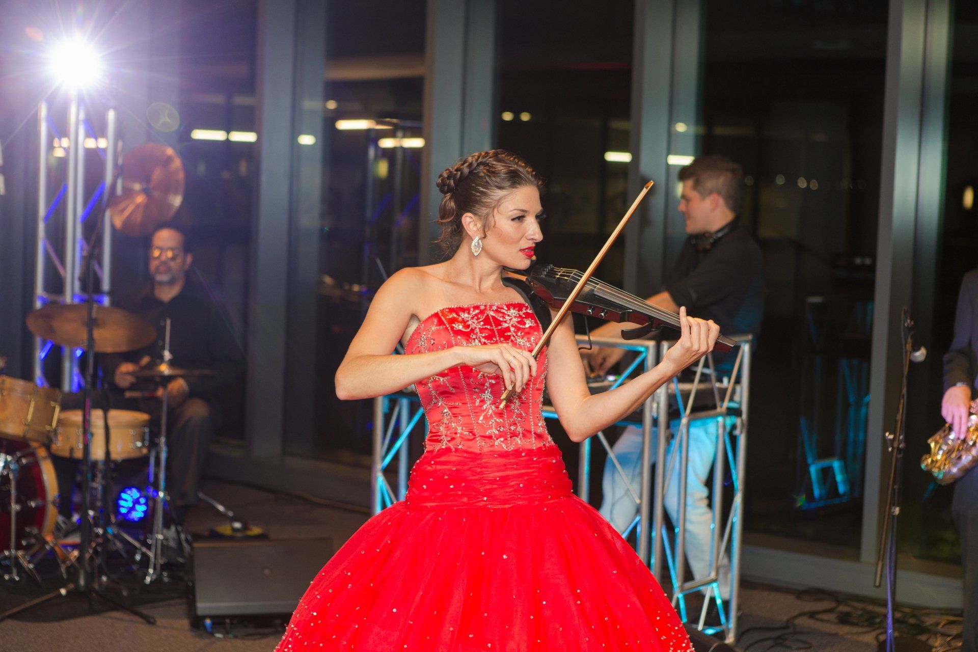 A woman in a red dress is playing a violin on stage.