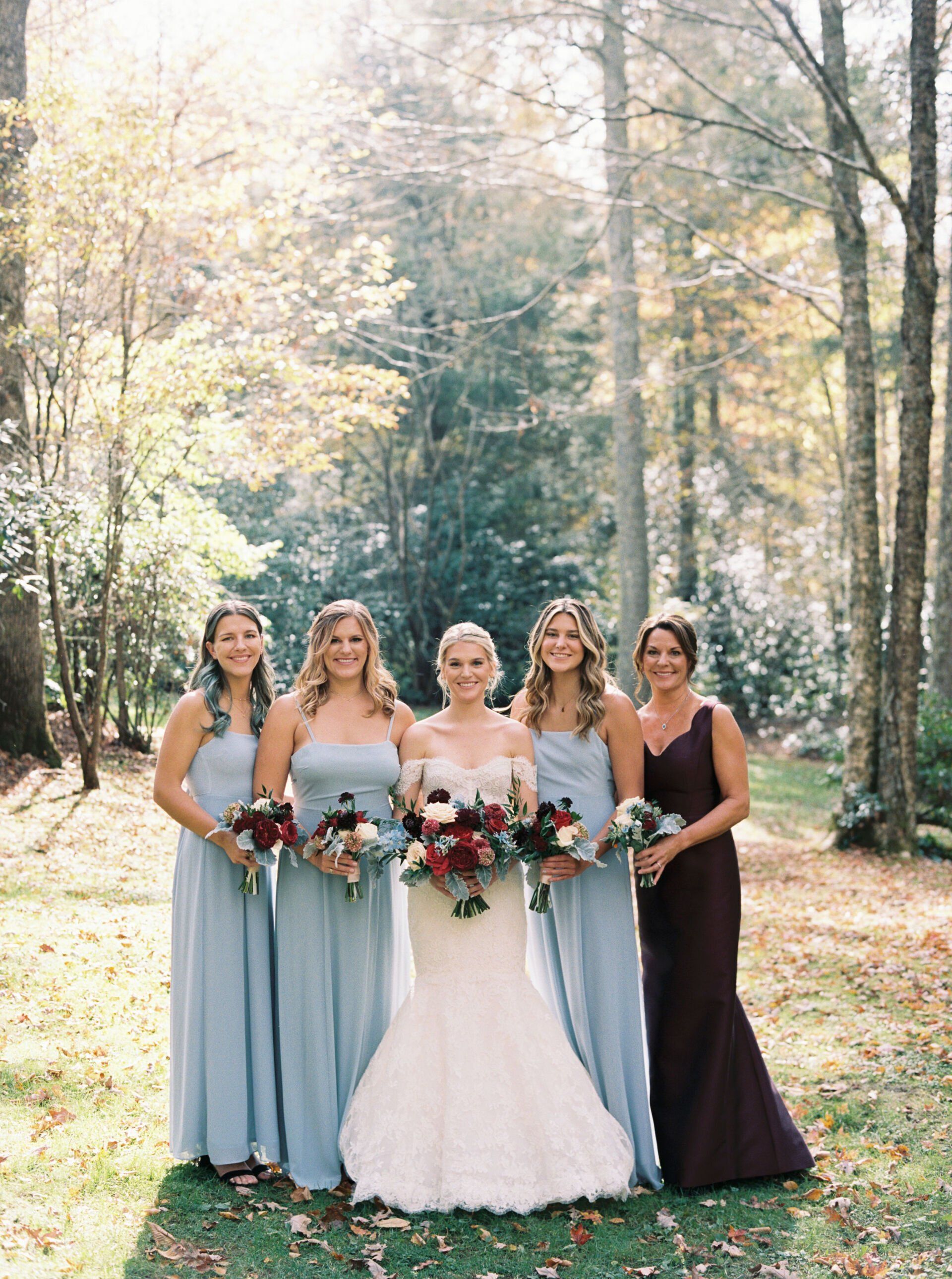 A bride and her bridesmaids are posing for a picture in the woods.