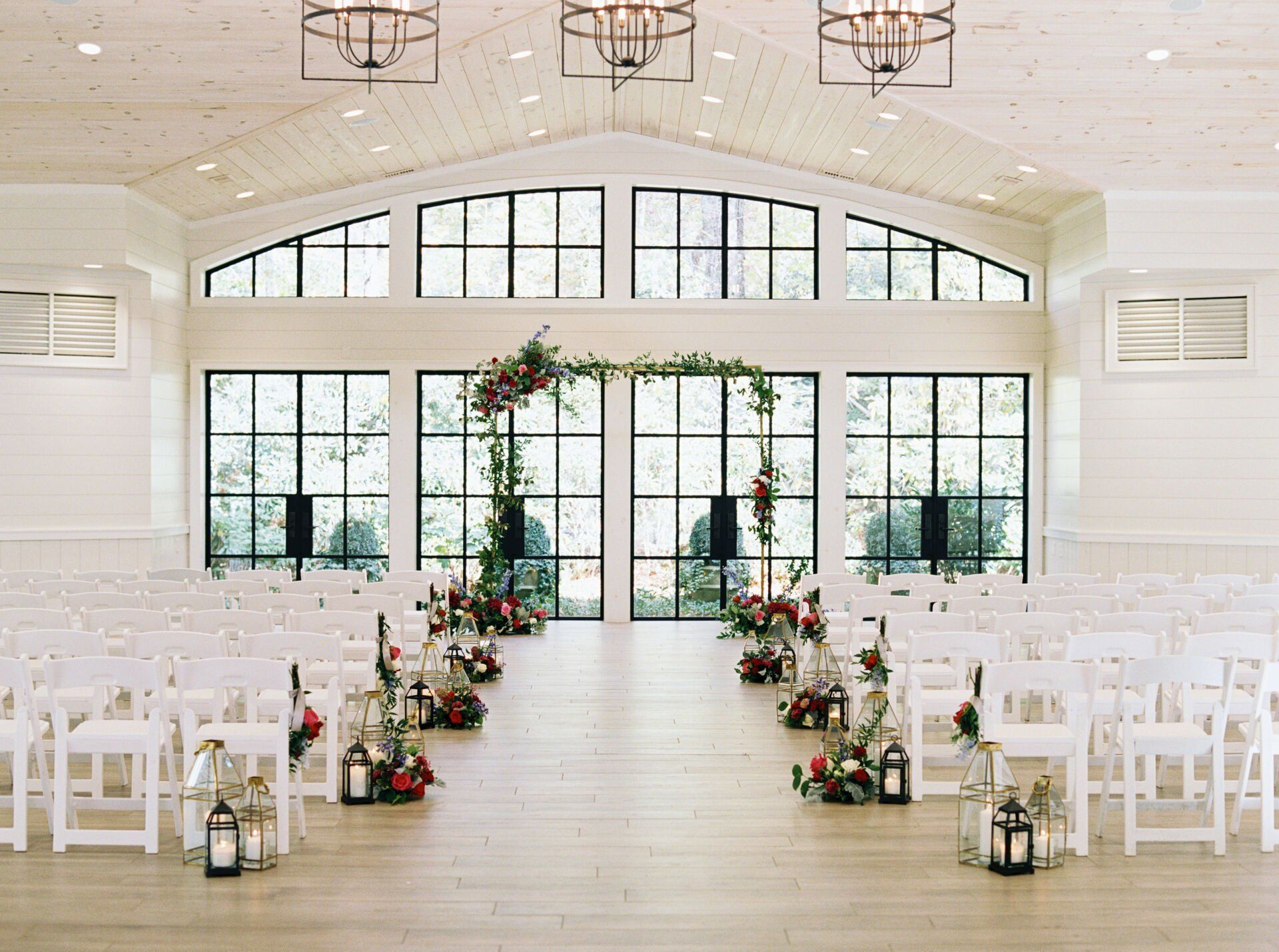 A wedding ceremony is taking place in a large room with lots of windows.