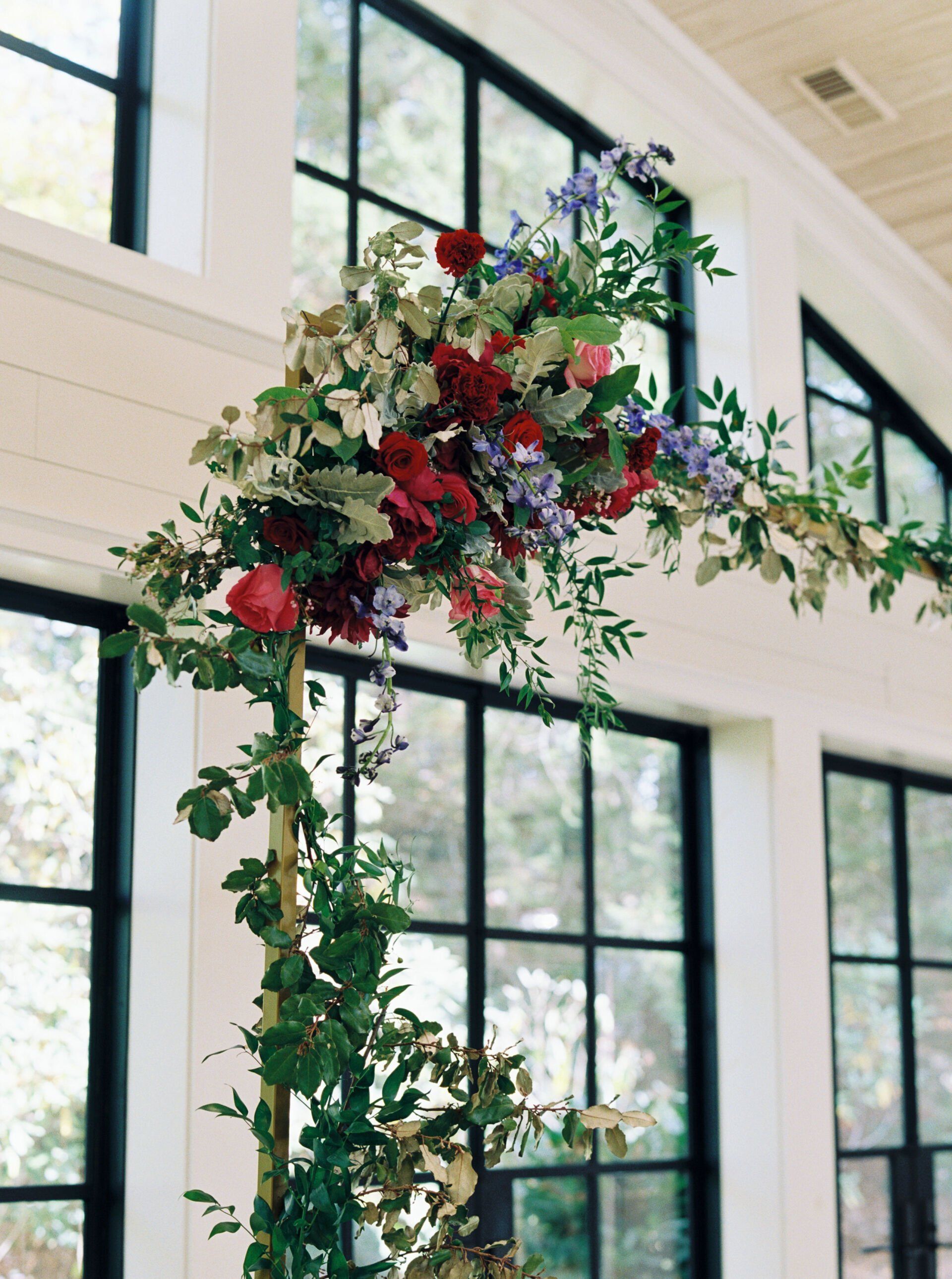 A bunch of flowers are hanging from the ceiling in front of a window.