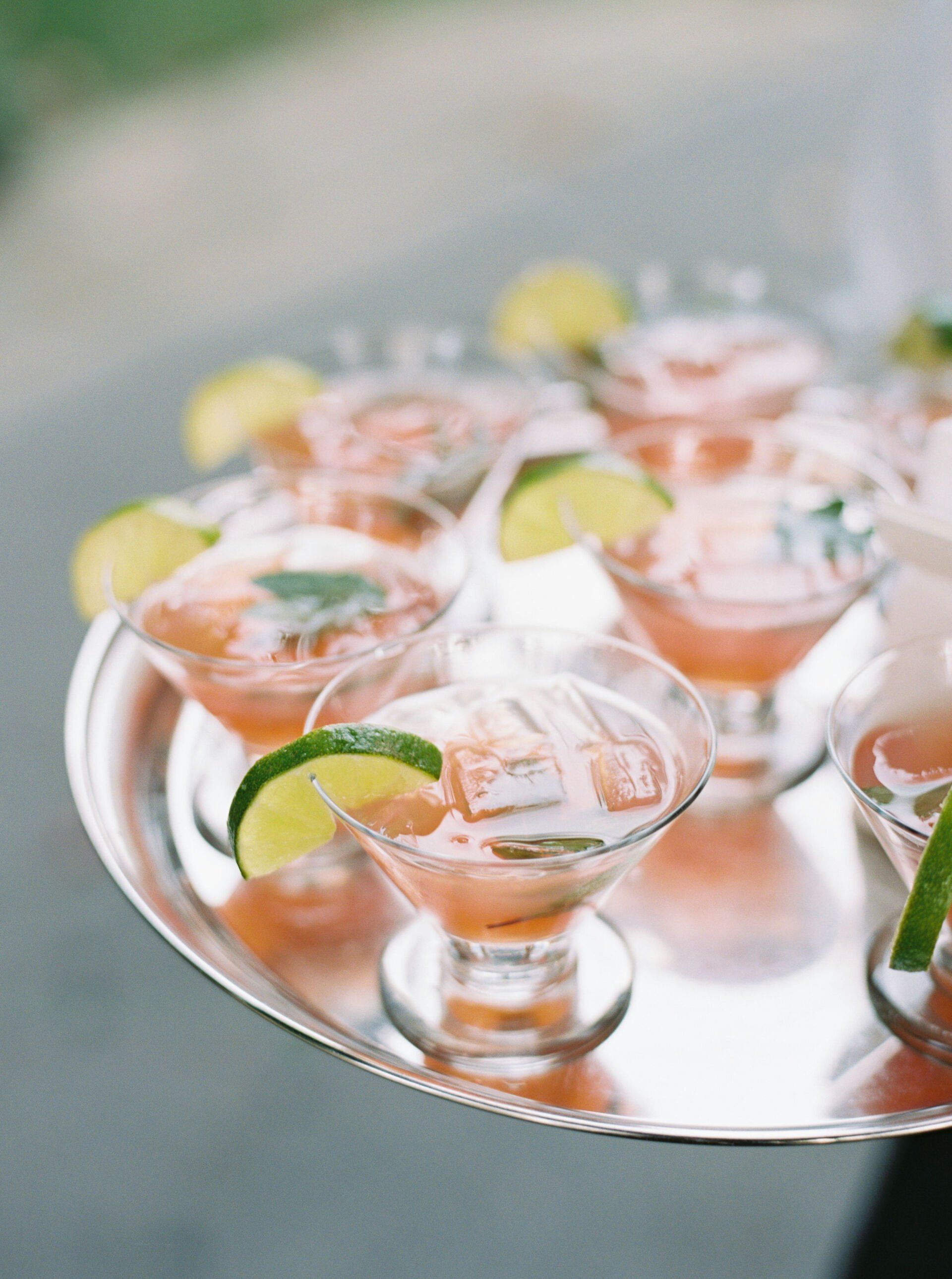 A tray of cocktails with lime slices on them