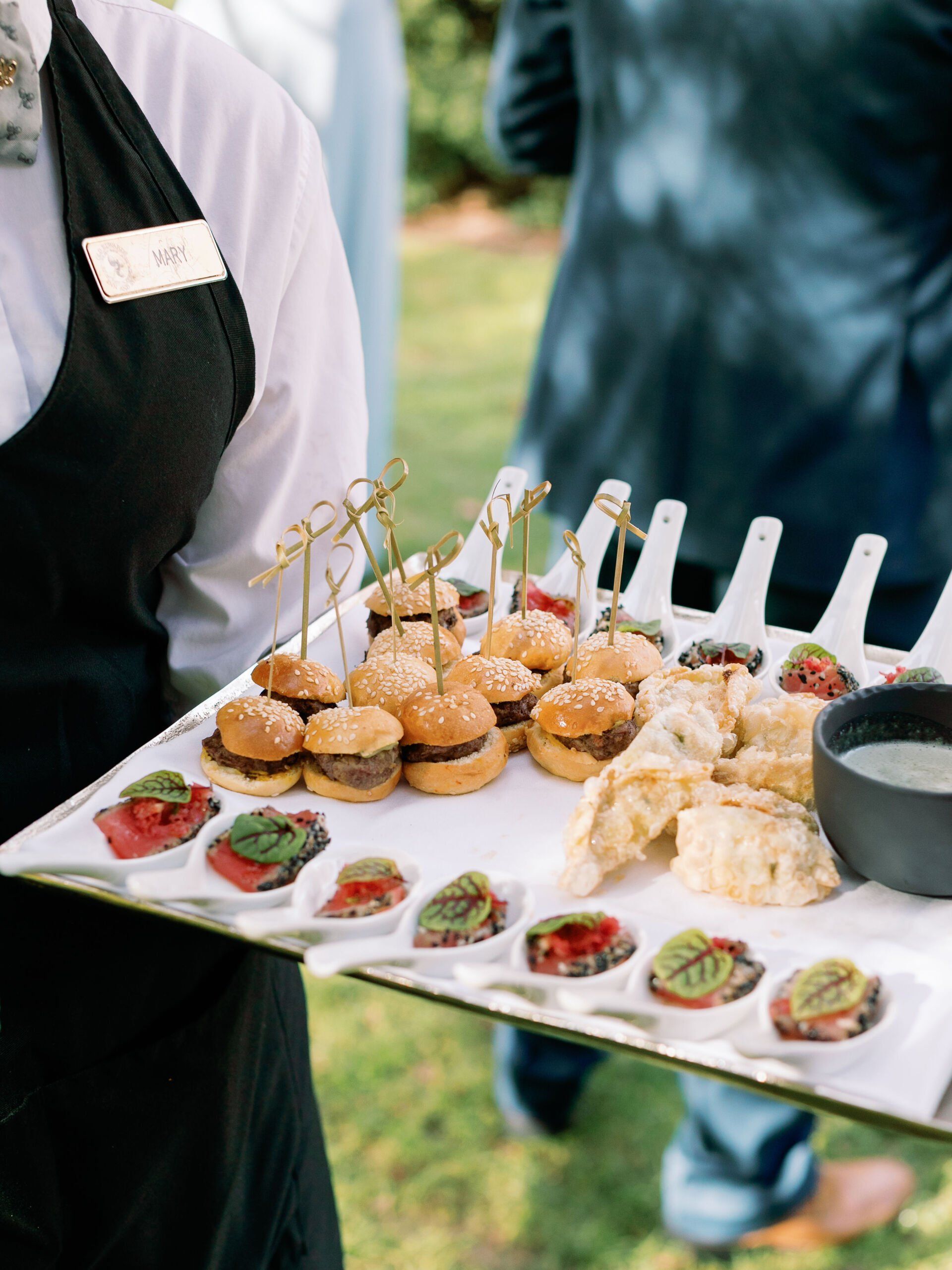 A person is holding a tray of food with a bowl of dipping sauce on it.