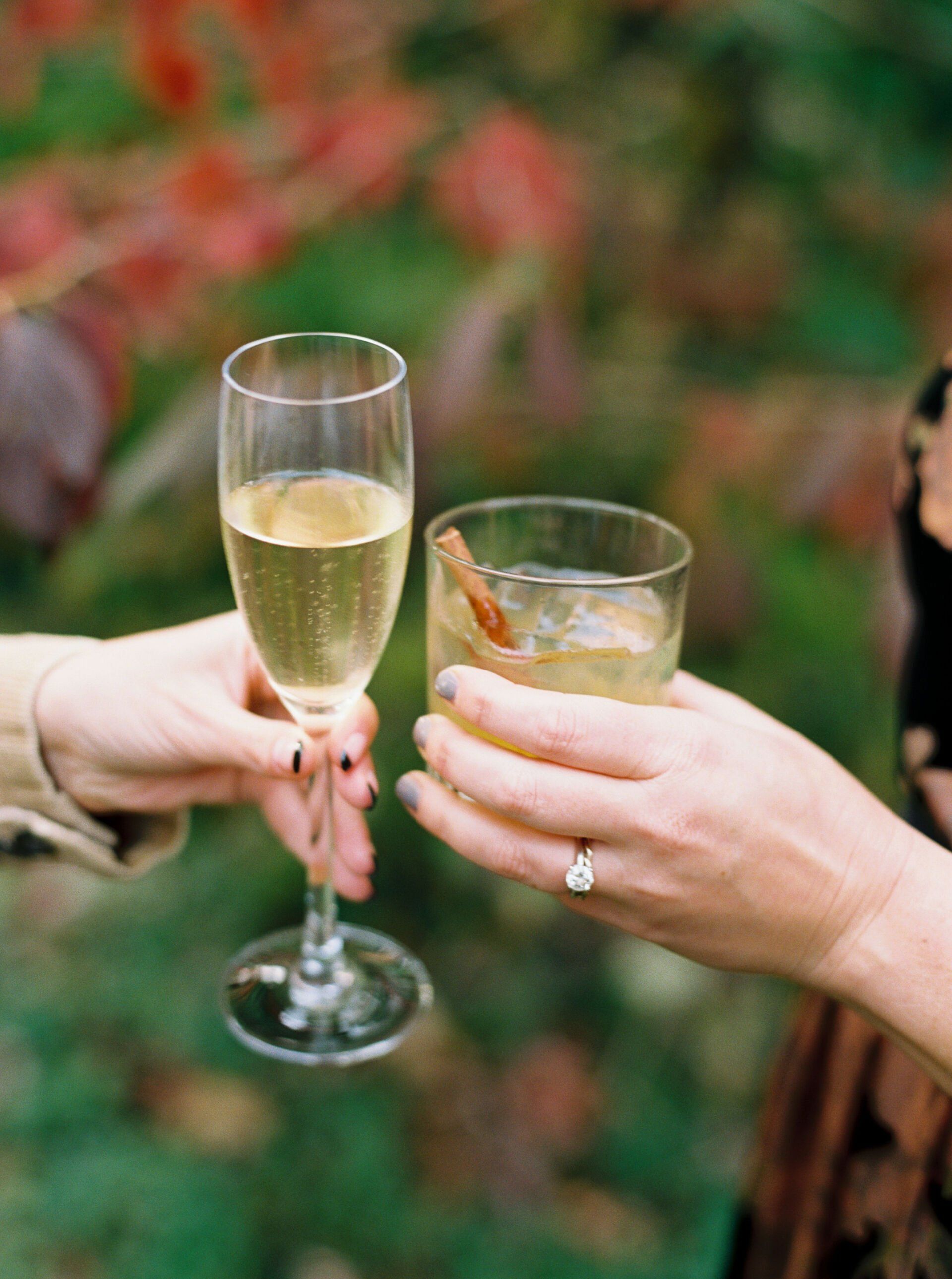 Two people are toasting with champagne glasses and a cinnamon stick.