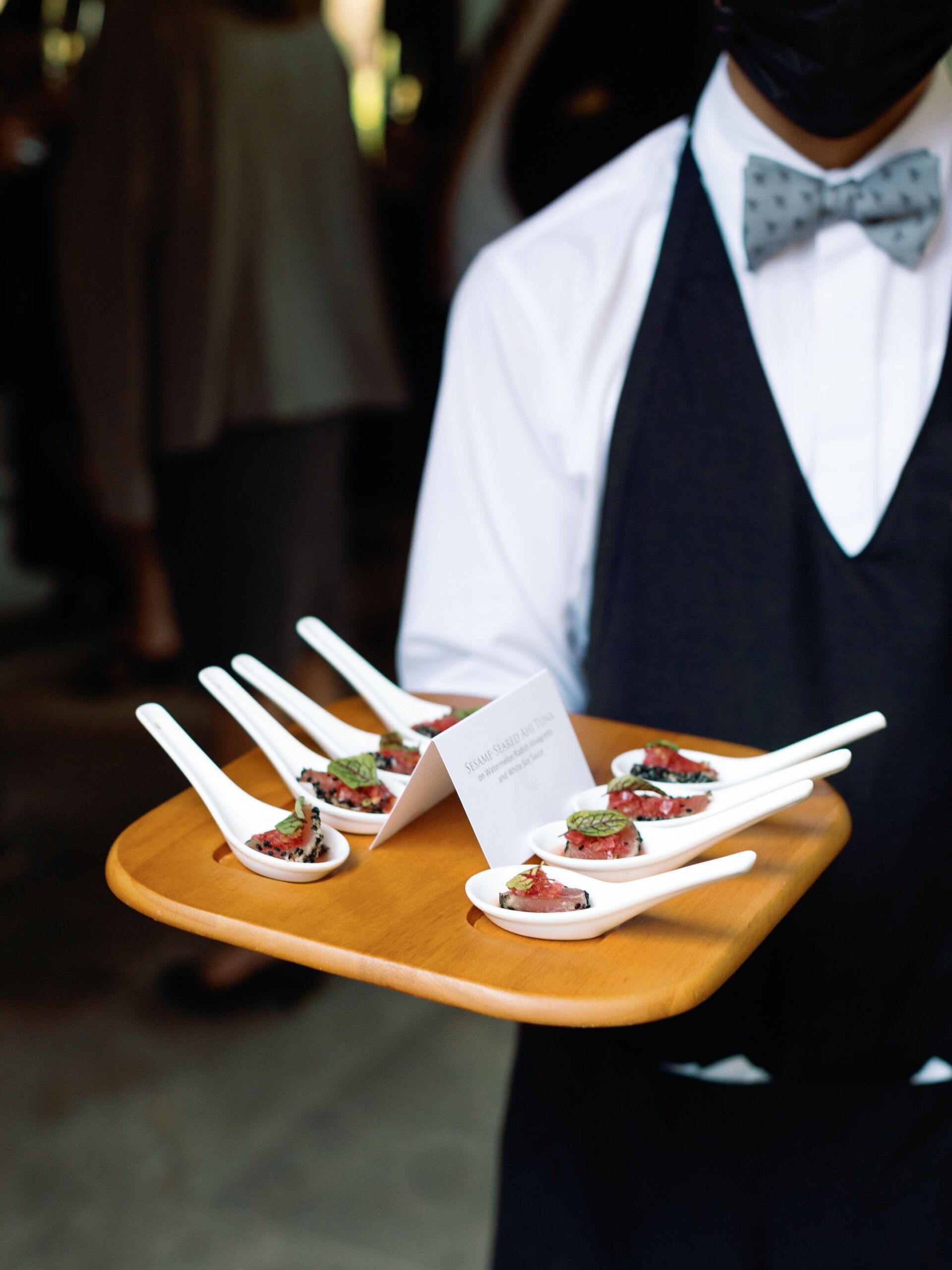 A man in a bow tie is holding a tray of food