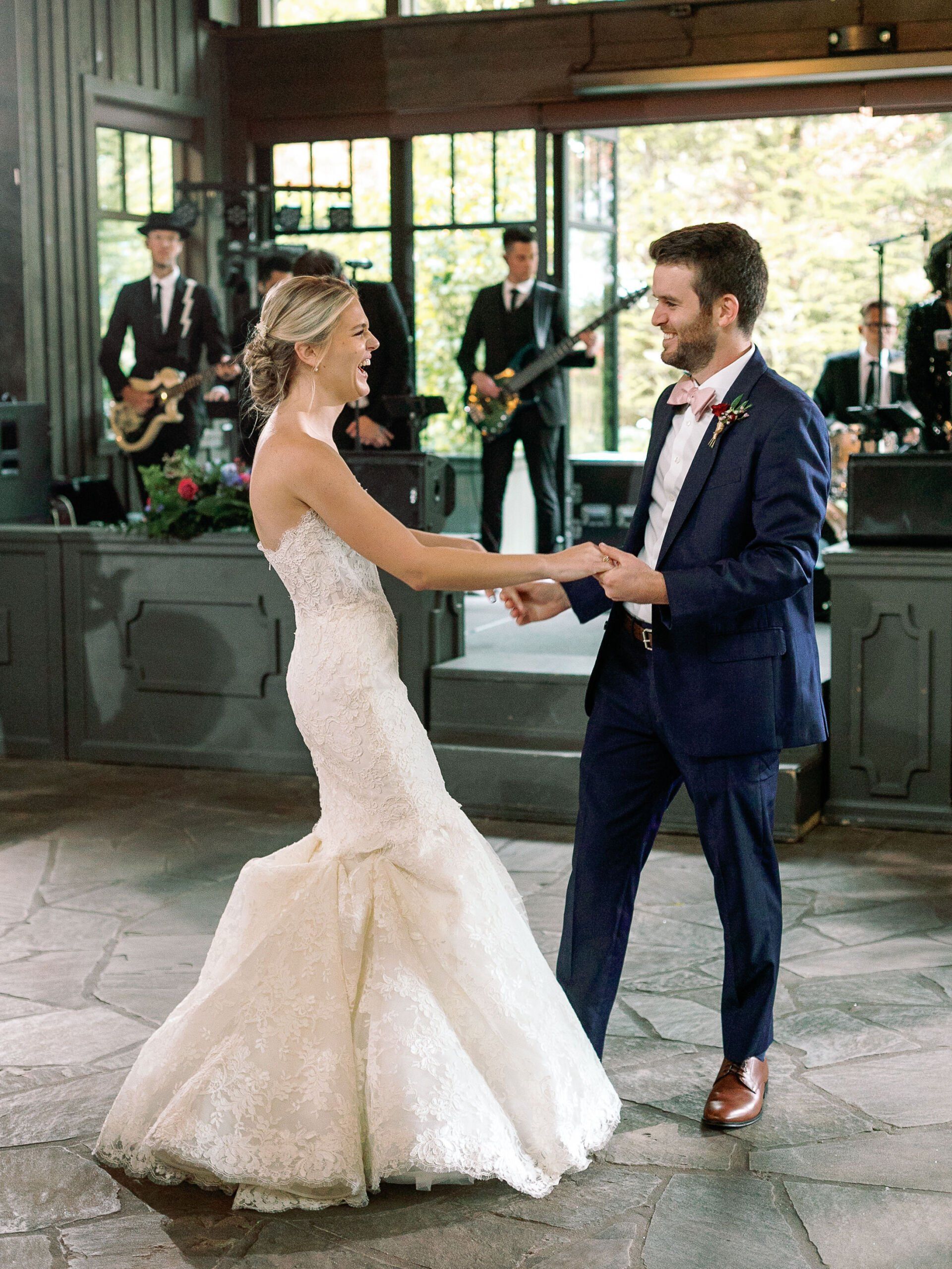 A bride and groom are dancing in front of a band.