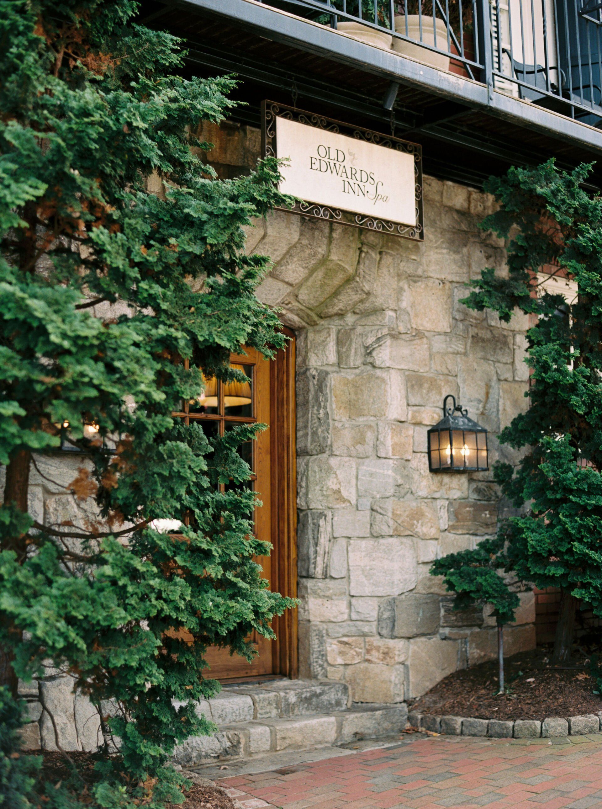A stone building with a sign above the door and trees in front of it.