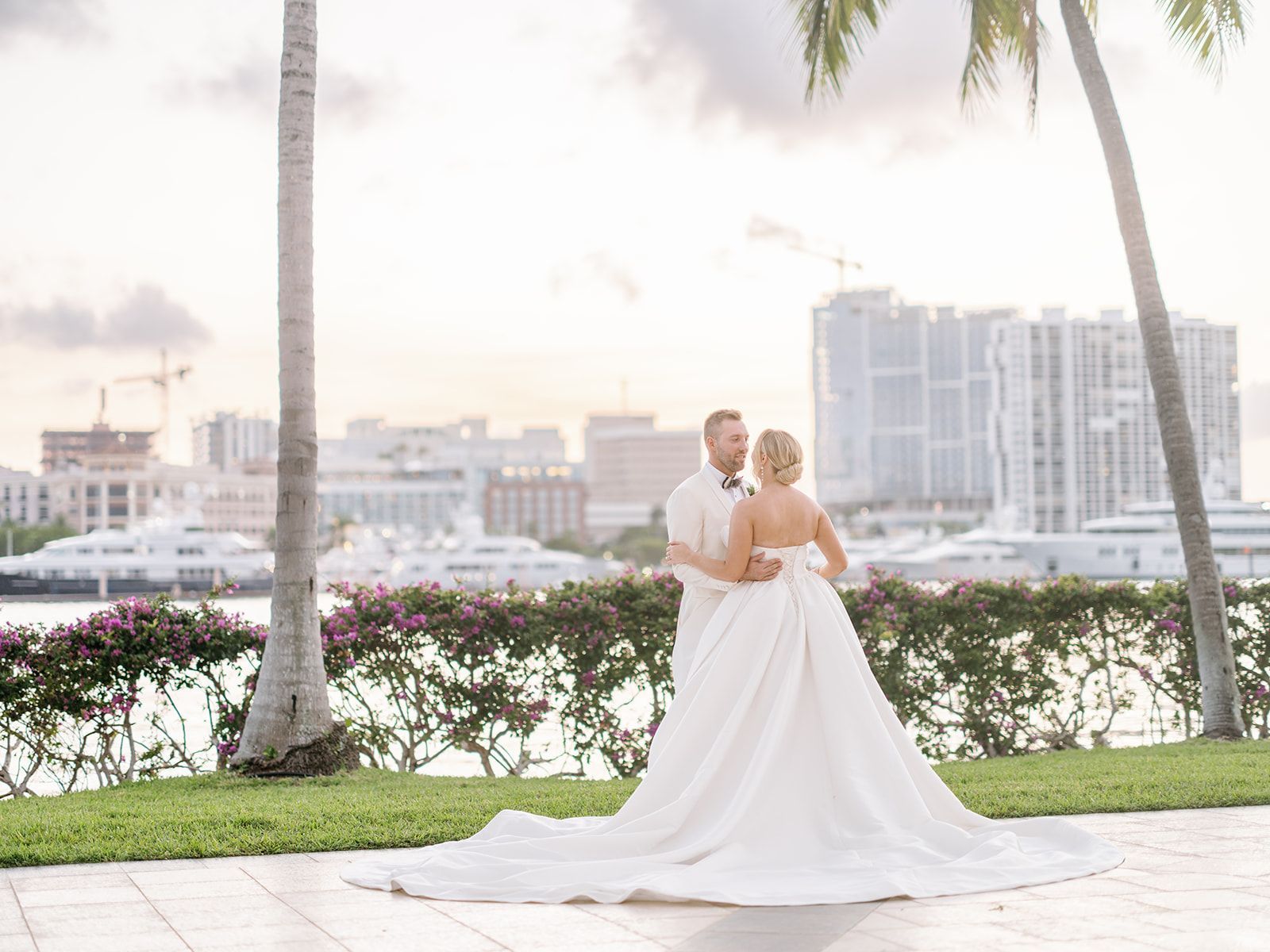 A bride and groom are standing next to each other in front of a city skyline.