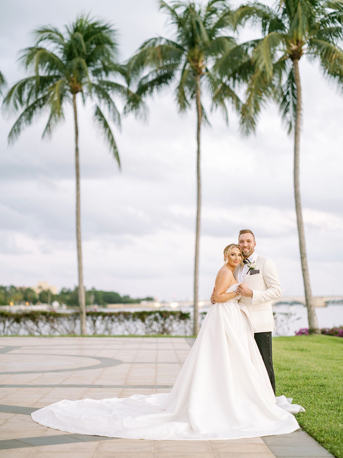 A bride and groom are posing for a picture in front of palm trees.