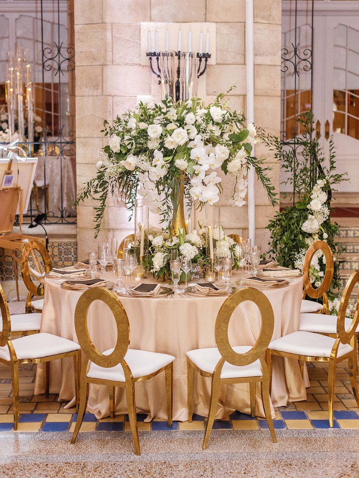 A table set for a wedding reception with a vase of flowers on it.