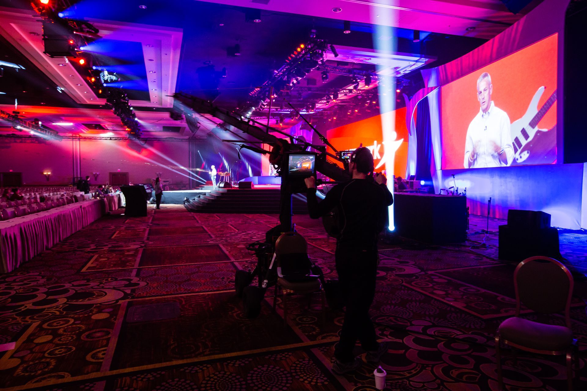 A man is standing in front of a large screen in a large room.