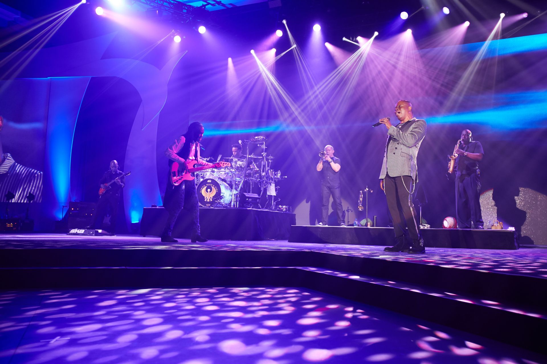 A man singing into a microphone on a stage with a band behind him