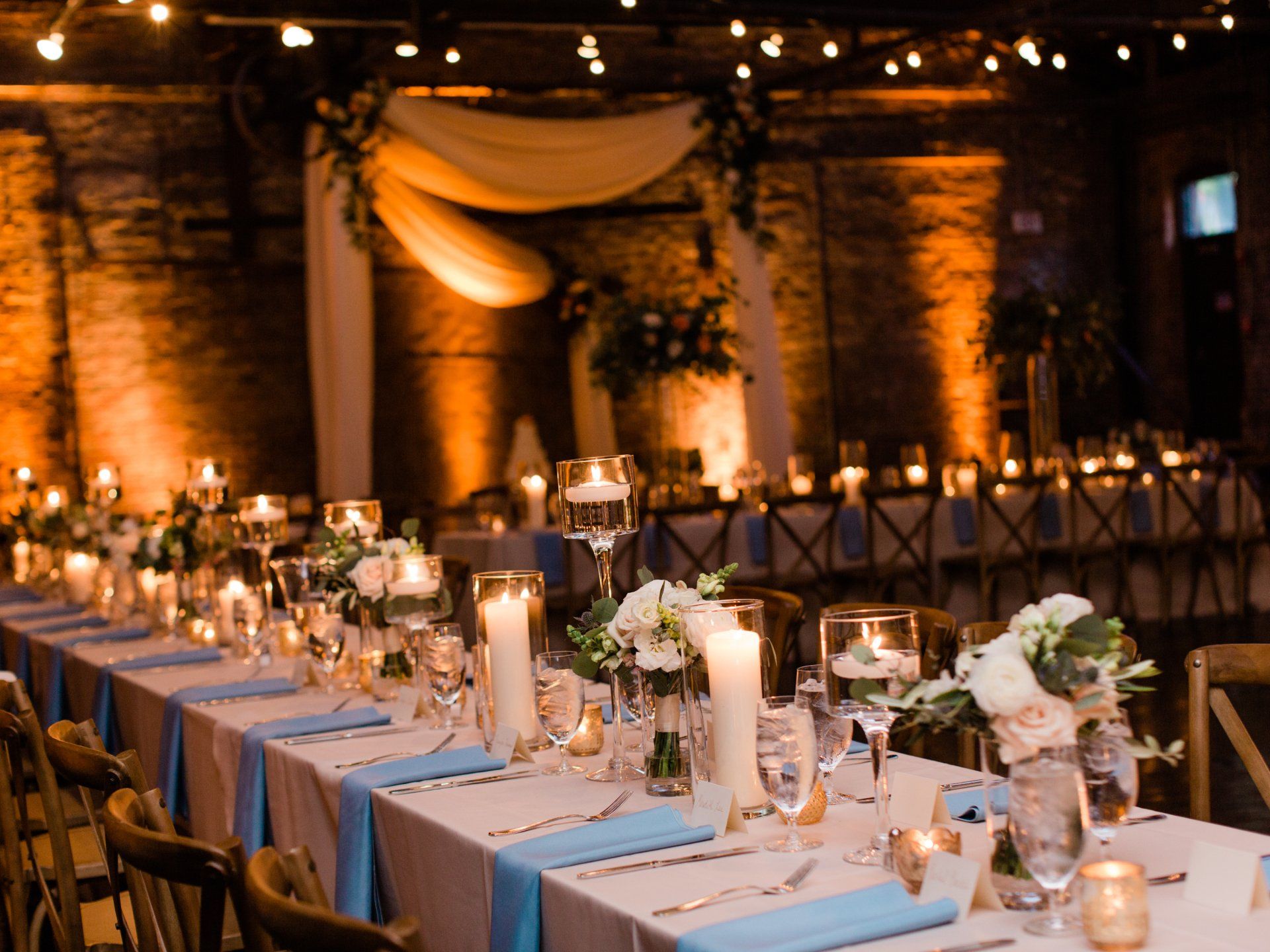 A long table is set for a wedding reception with candles and flowers.