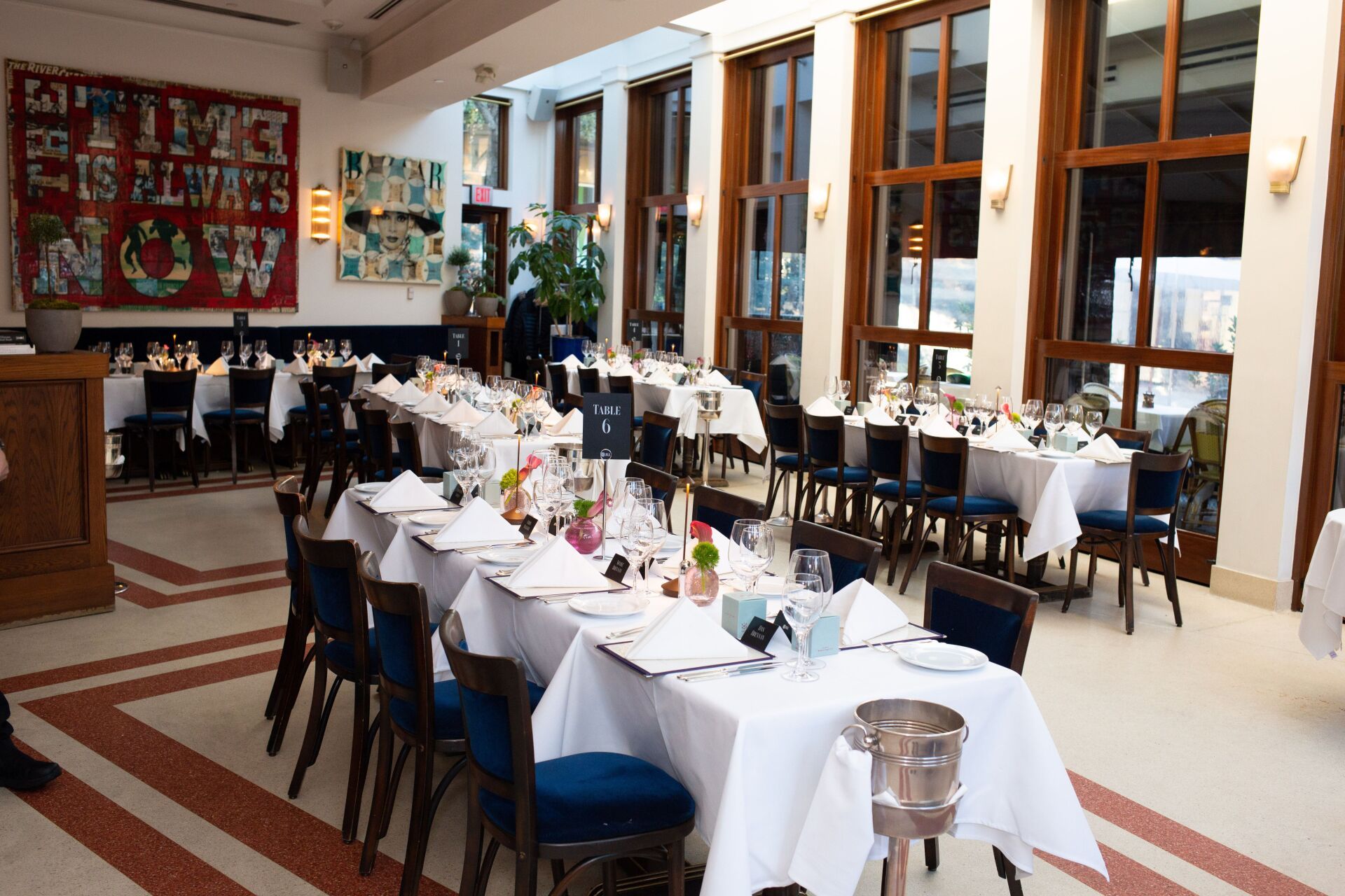 A large dining room with tables and chairs and a sign on the wall that says it 's always sunny