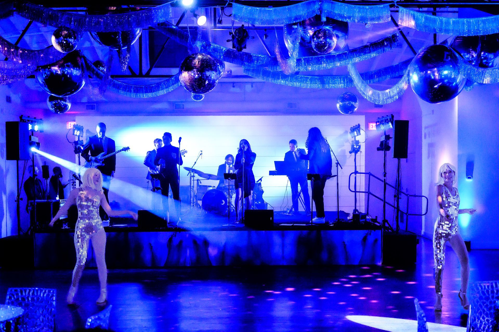 A group of people are standing on a stage in a room with blue lights.