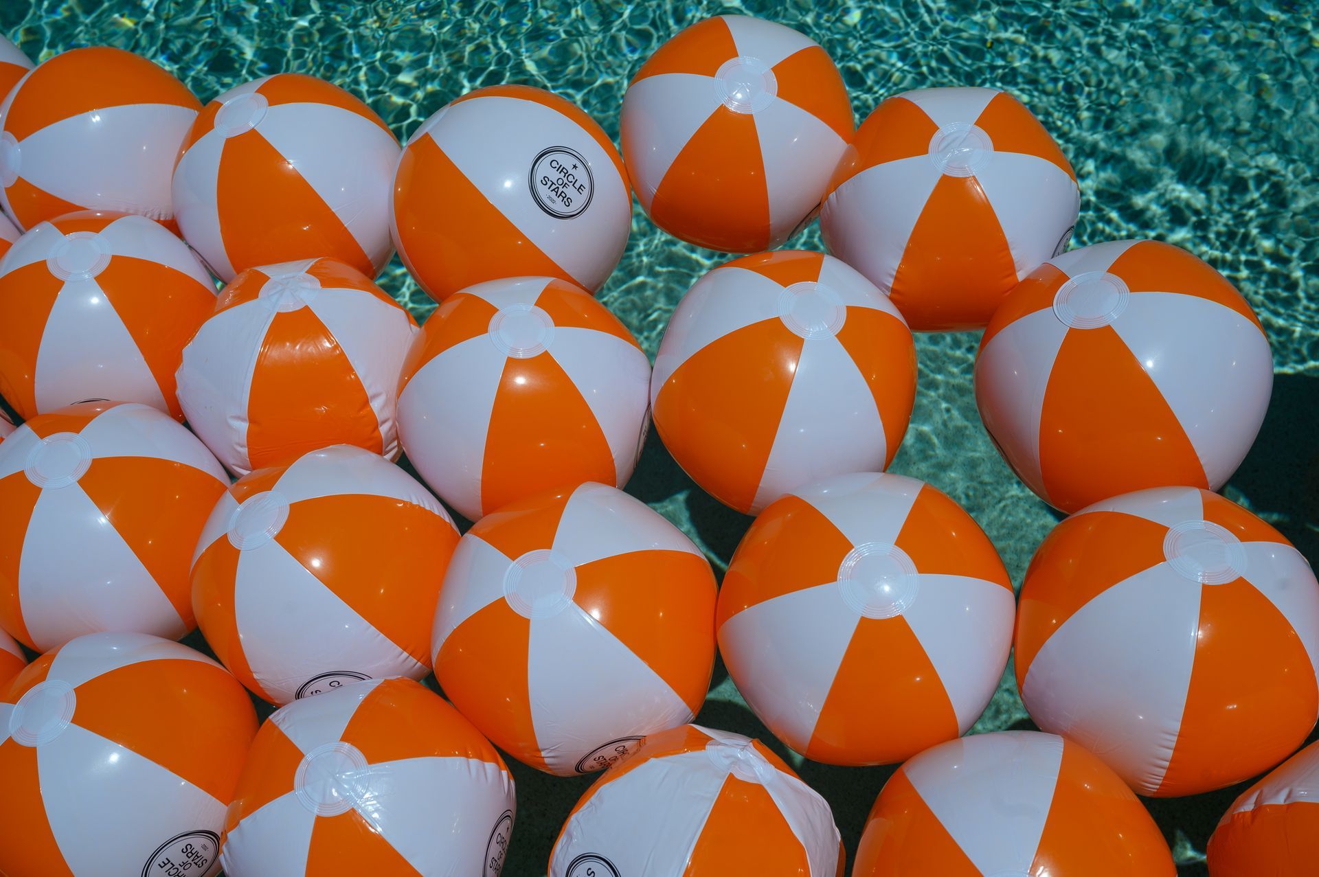A bunch of orange and white beach balls in a pool