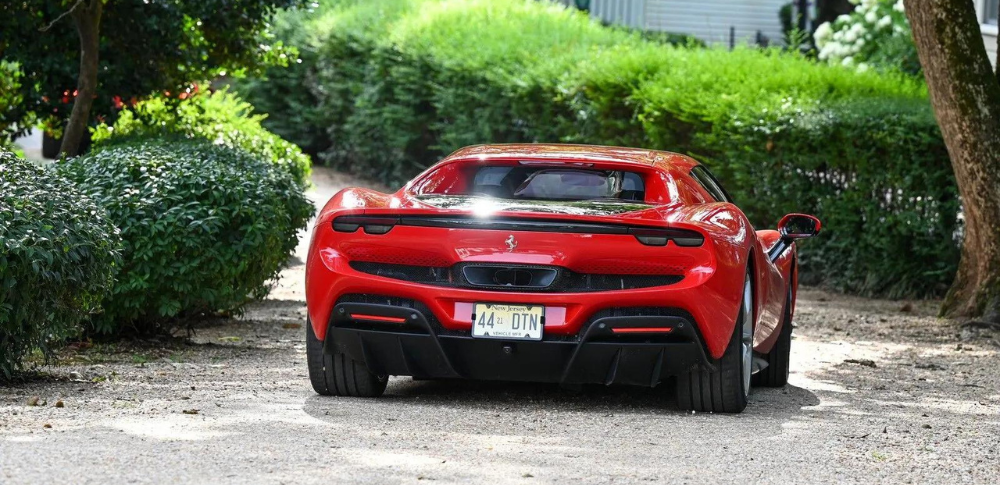 A red sports car is parked on the side of a dirt road.