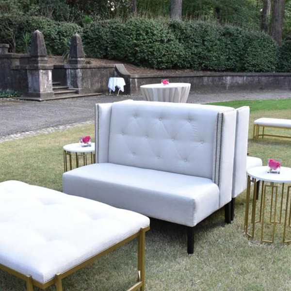 A white couch and ottoman are sitting in the grass