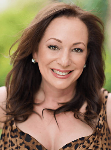 A woman in a leopard print top smiles for the camera