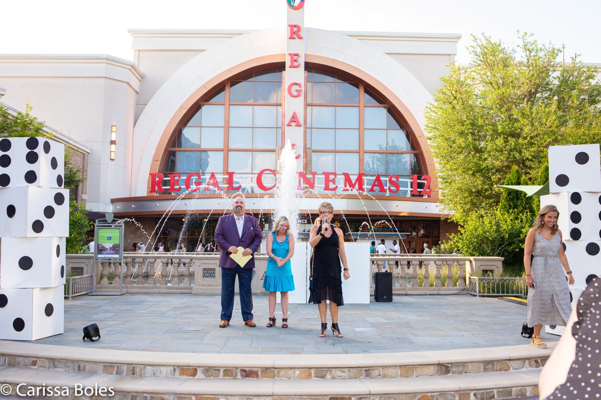 A group of people standing in front of a regal cinemas building.