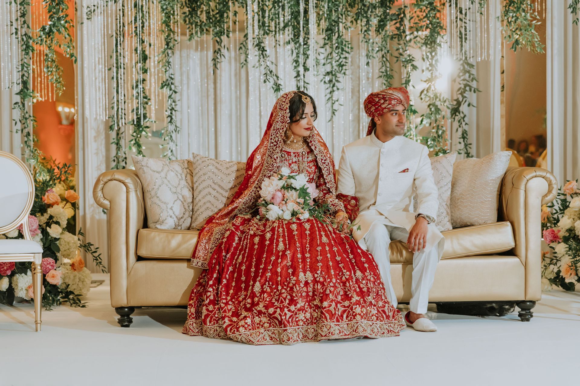 a bride and groom are sitting on a couch at their wedding .