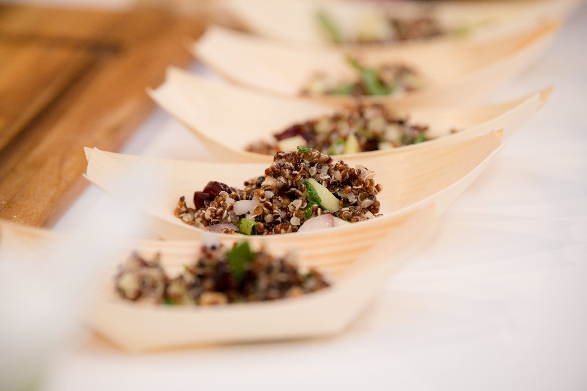 A row of wooden spoons filled with food on a table.