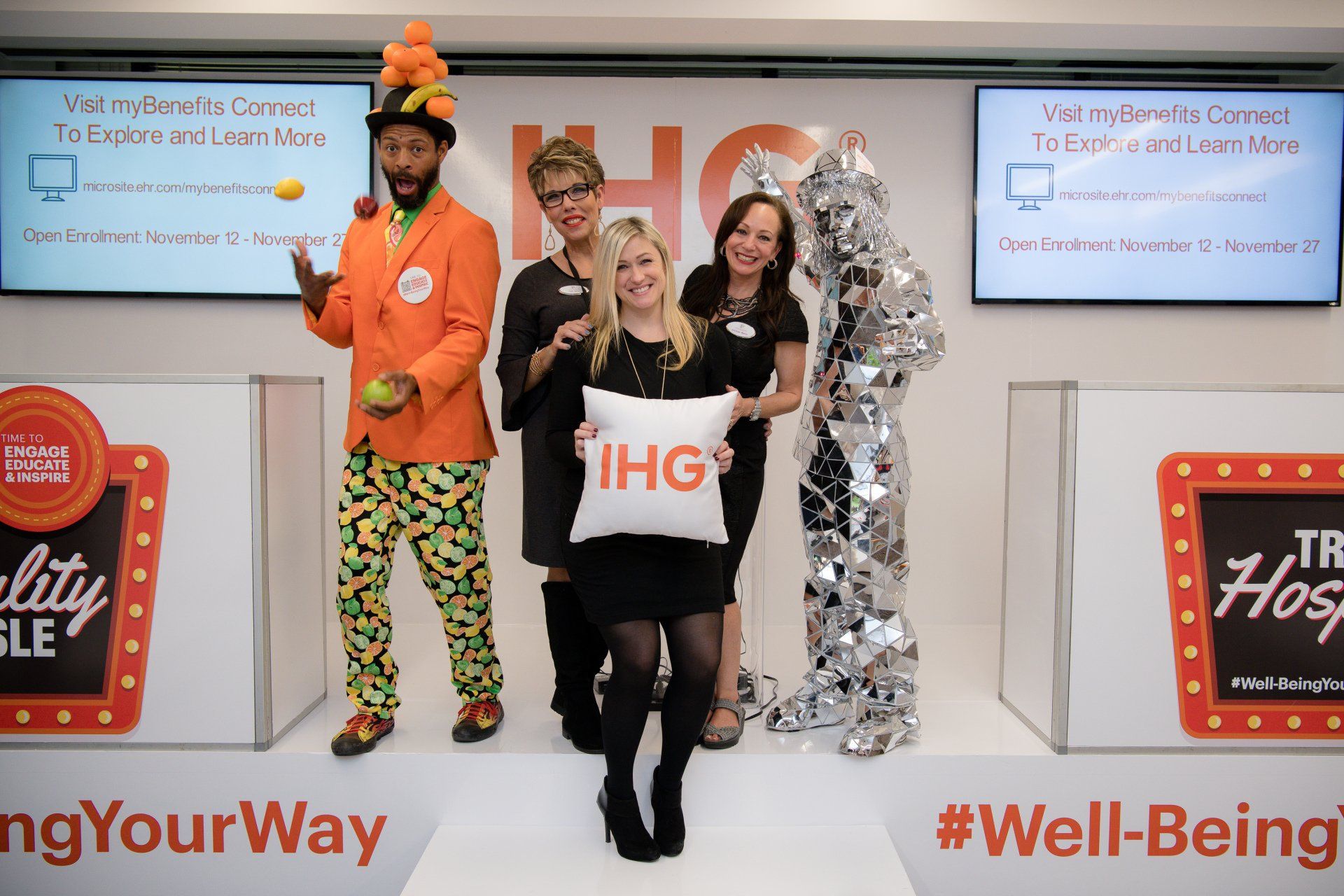 A woman is holding a pillow that says ihg on it