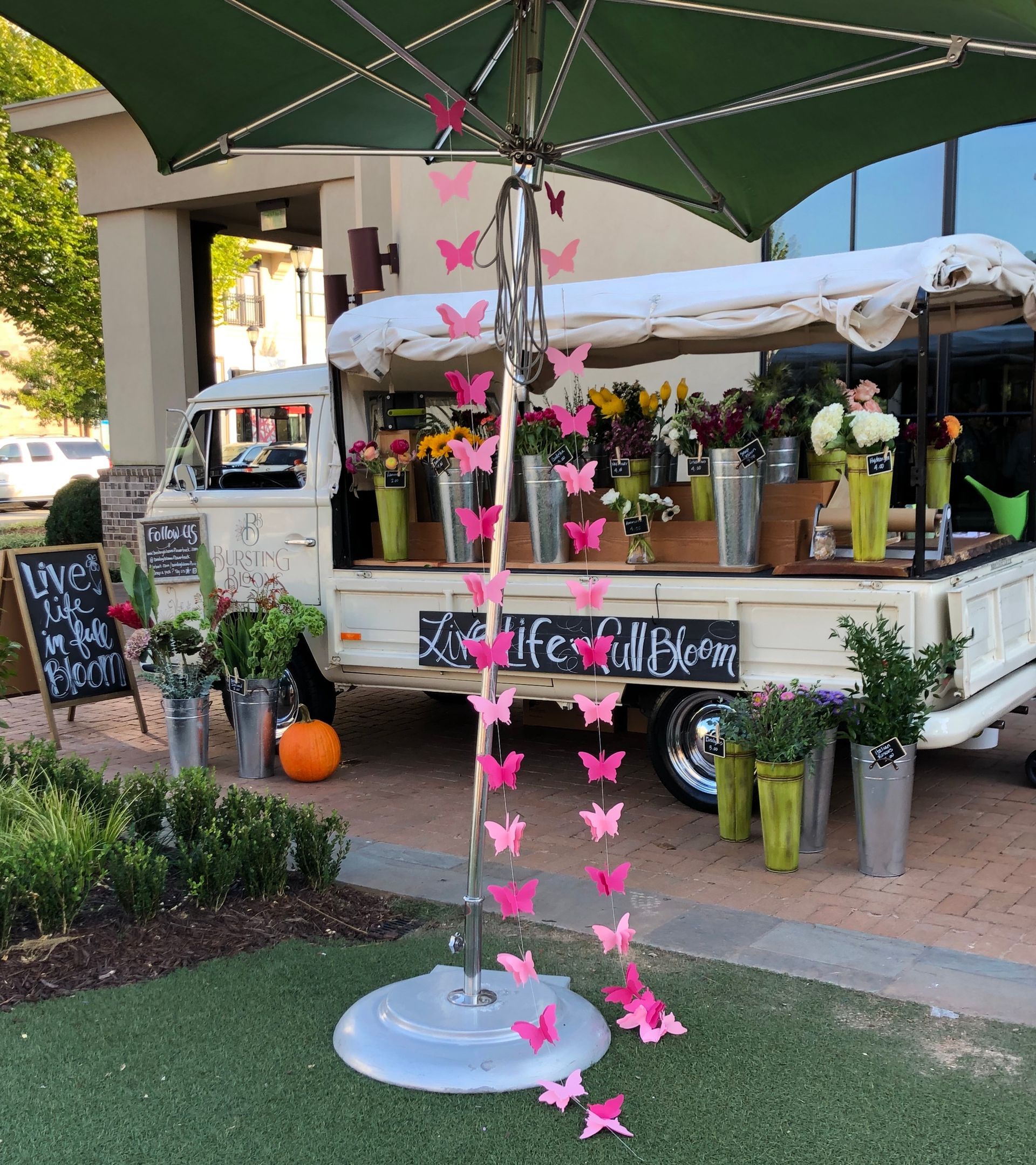 A truck with flowers on it is parked under an umbrella.