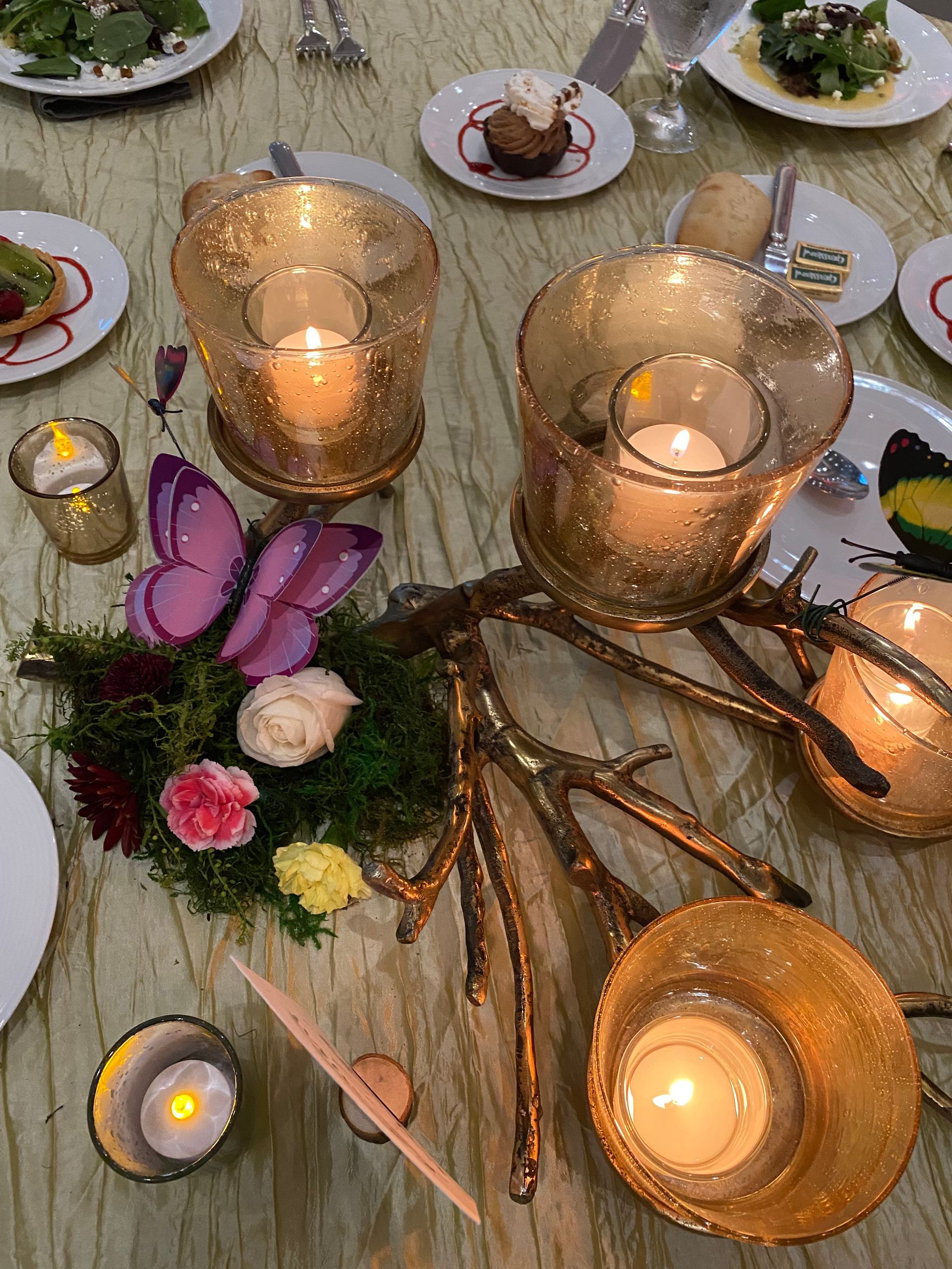A table with plates of food and candles on it.