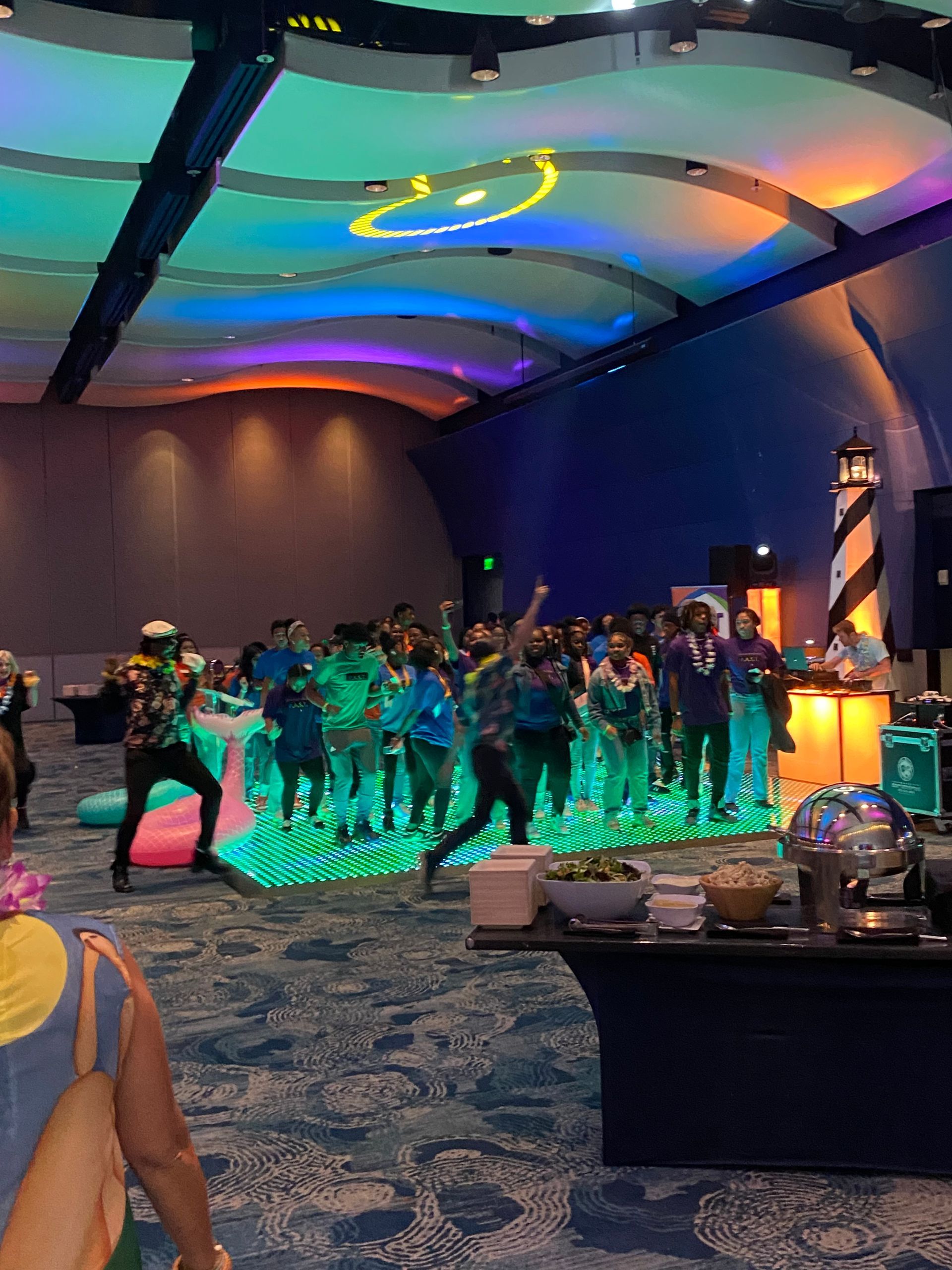 A group of people are dancing in a large room.